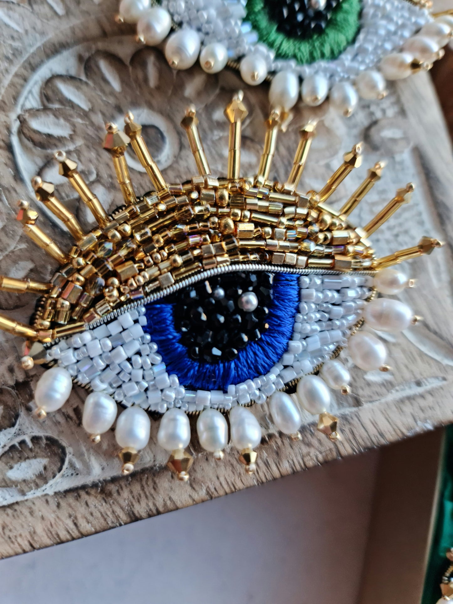 Lovers Blue Eye Beaded Brooch featuring a modern embroidery design with glass beads, crystals, and plastic beads arranged in a captivating blue eye, set on a felt backing, measuring 2.34 inches by 2.14 inches (6 cm x 5.5 cm).