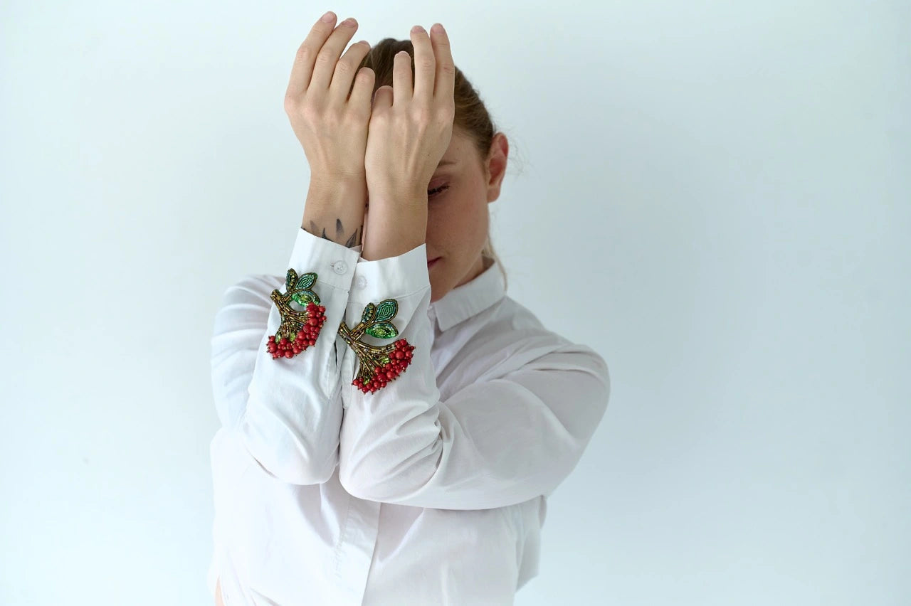 Person wearing a white shirt with decorative cuffs against a light background