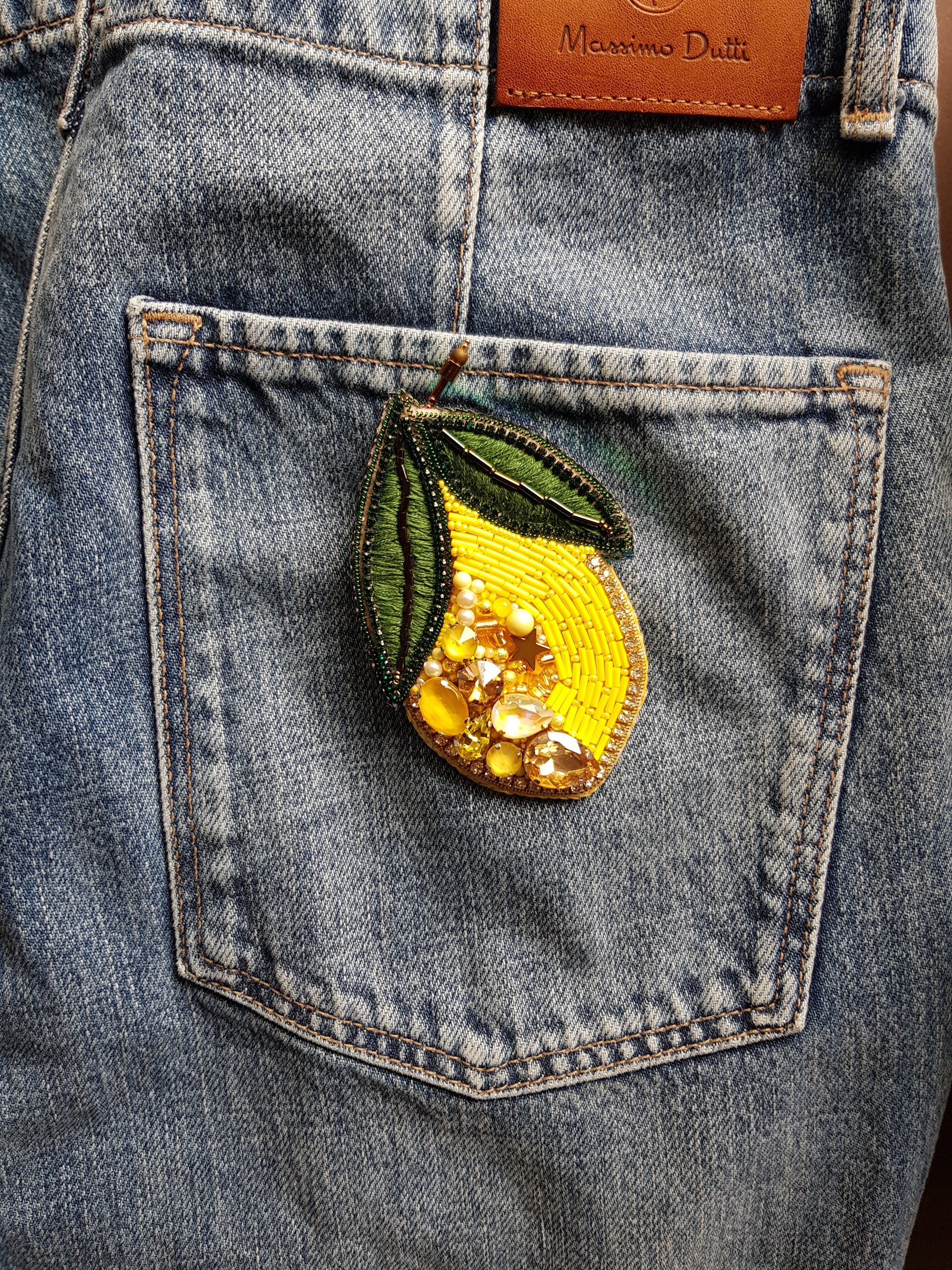 Denim pocket with a decorative lemon patch and 'Max Mara' brand label.