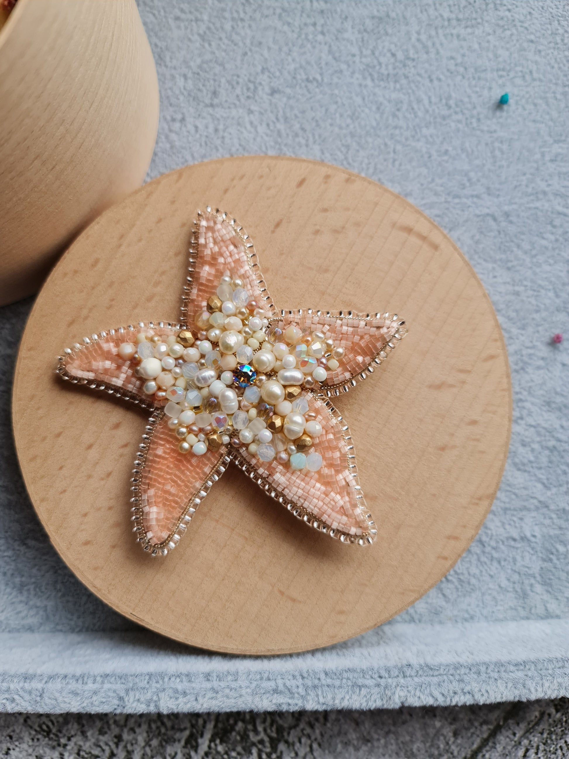 Model wearing the Stellar Seas Starfish Brooch as a statement accessory, highlighting its ocean-inspired design with warm peach, beige, and golden tones.