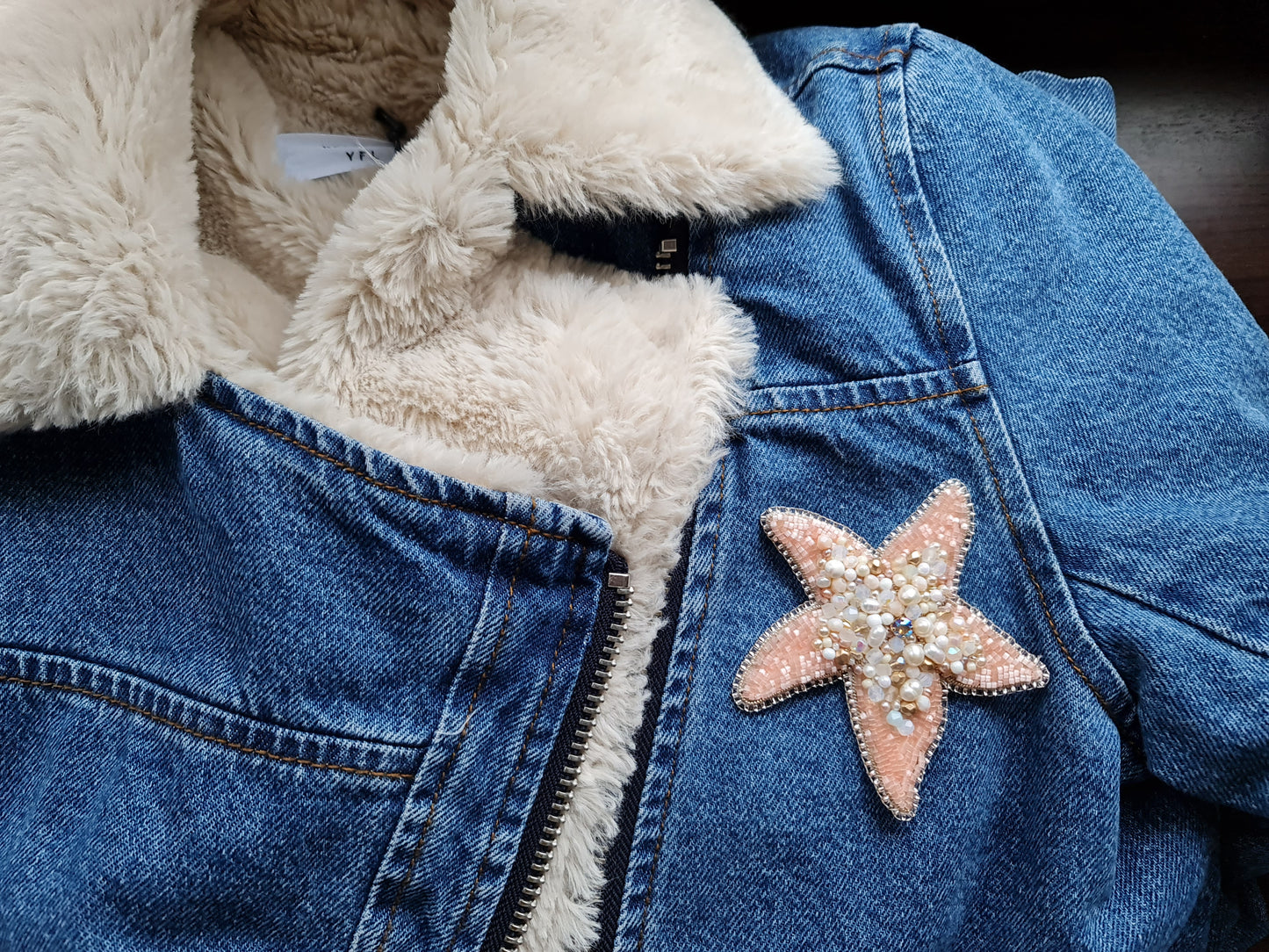 Model wearing the Stellar Seas Starfish Brooch as a statement accessory, highlighting its ocean-inspired design with warm peach, beige, and golden tones.