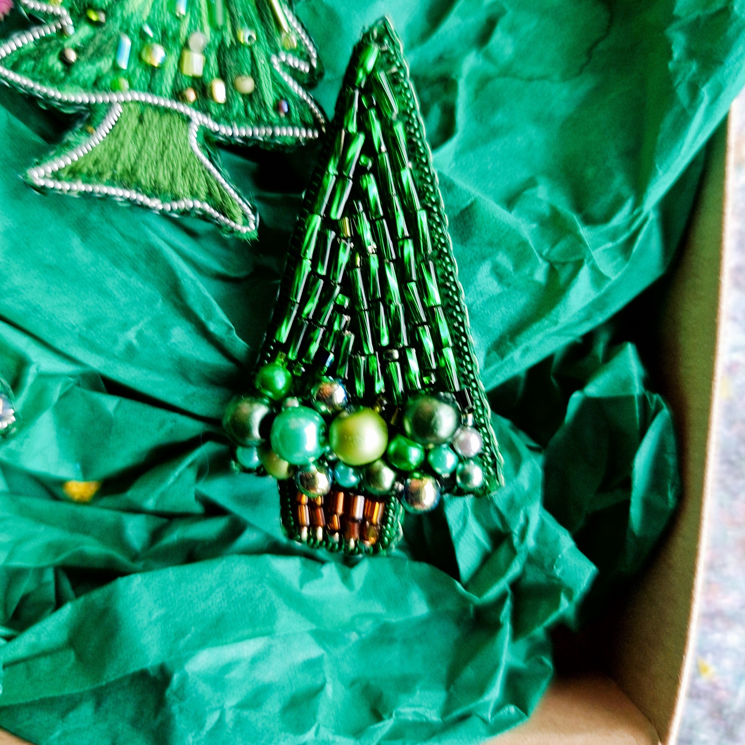 Decorative green beaded Christmas tree ornament on crumpled green paper