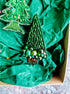 Decorative green beaded Christmas tree ornament on crumpled green paper