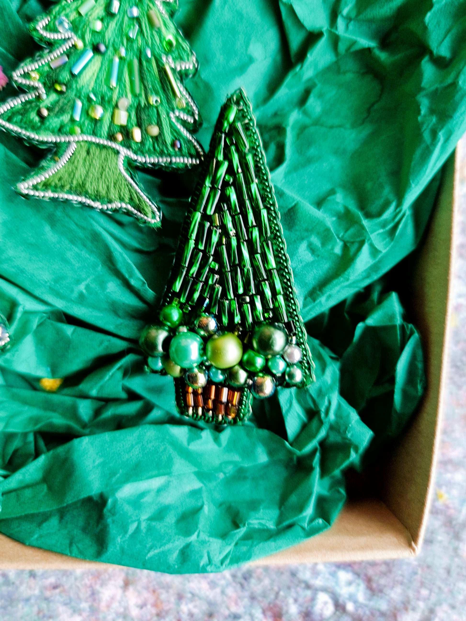 Decorative green beaded Christmas tree ornament on crumpled green paper