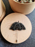 Black beaded umbrella brooch on a wooden surface with a dark background