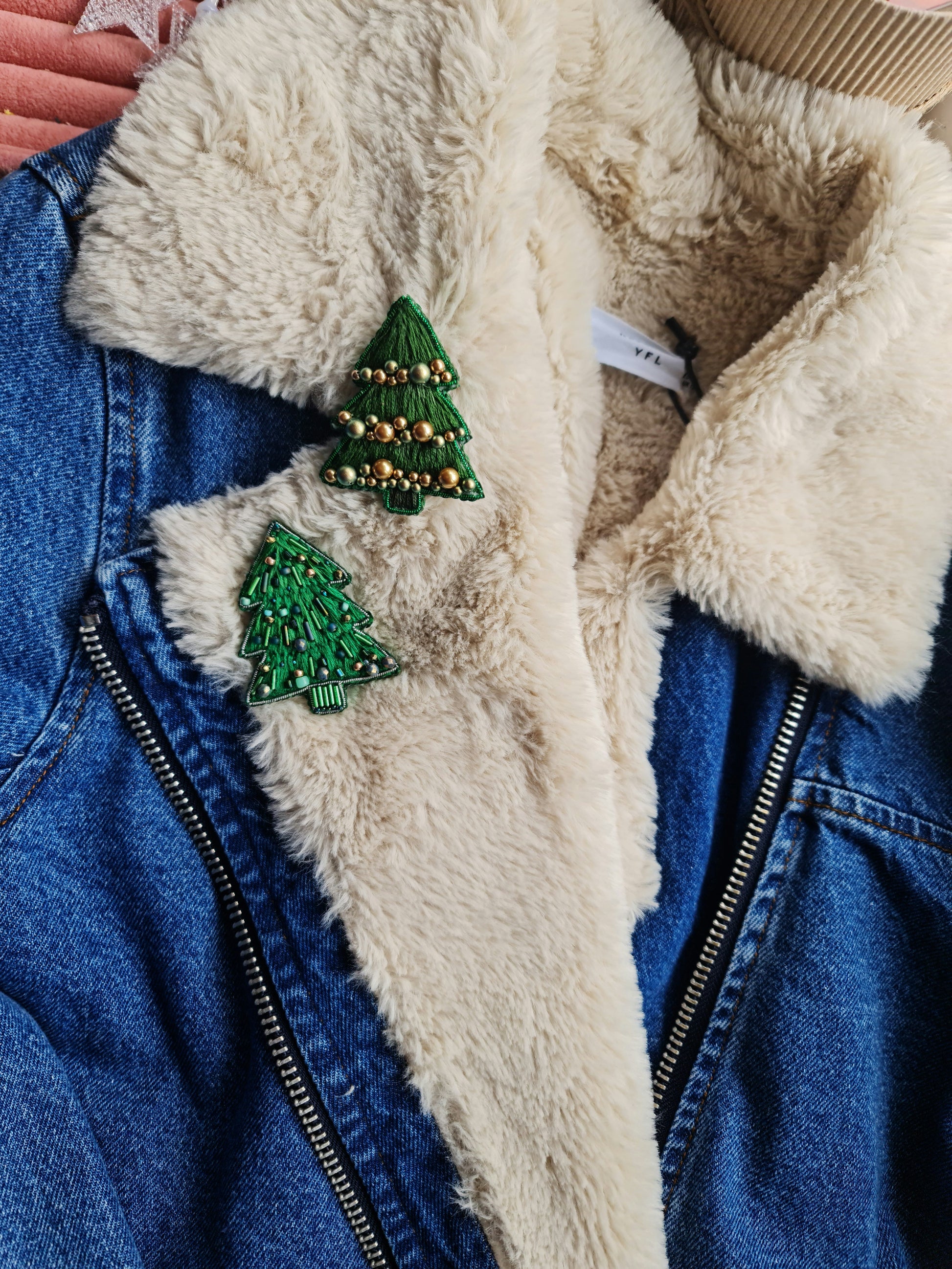 Blue denim jacket with white fur lining and green Christmas tree pins.