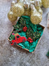 Decorative Christmas wreath with red car and holly berries in a box, surrounded by gold light bulbs on a textured surface.