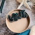 Decorative brooches on a round beige surface with a blurred background