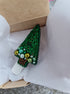 Green beaded brooch on a white shirt with a cardboard box in the background