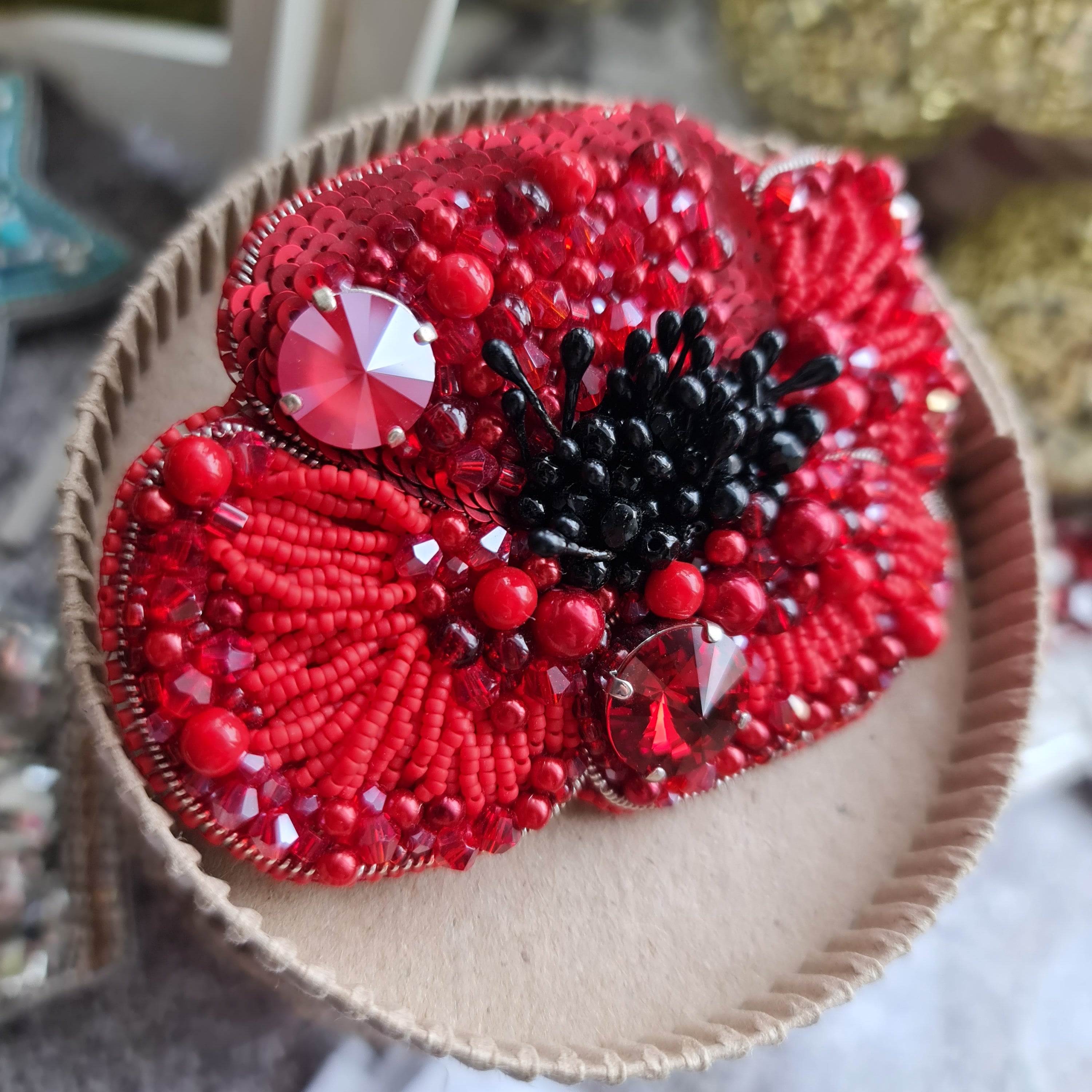Red beaded flower brooch on a textured surface