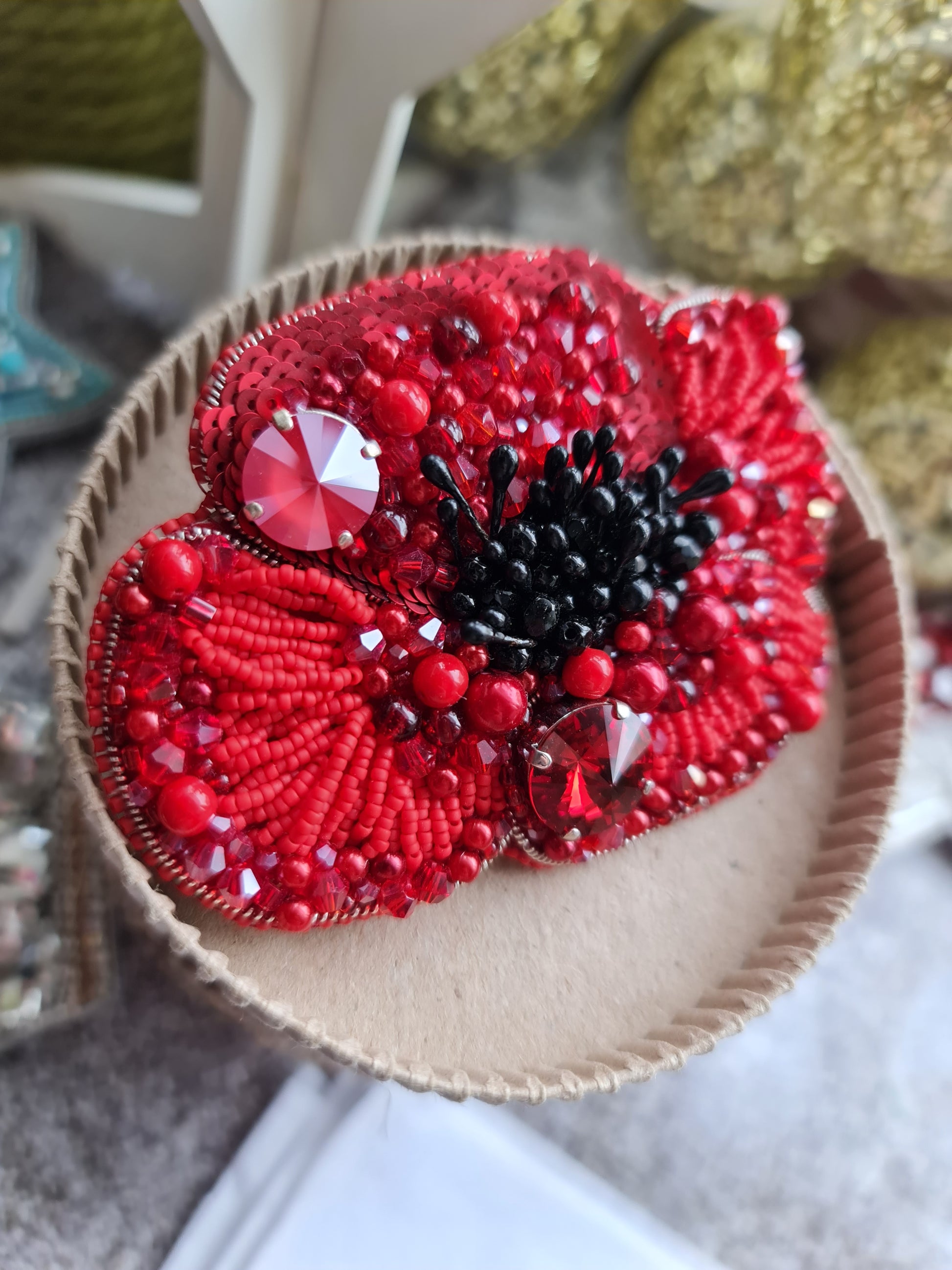 Red beaded flower brooch on a textured surface