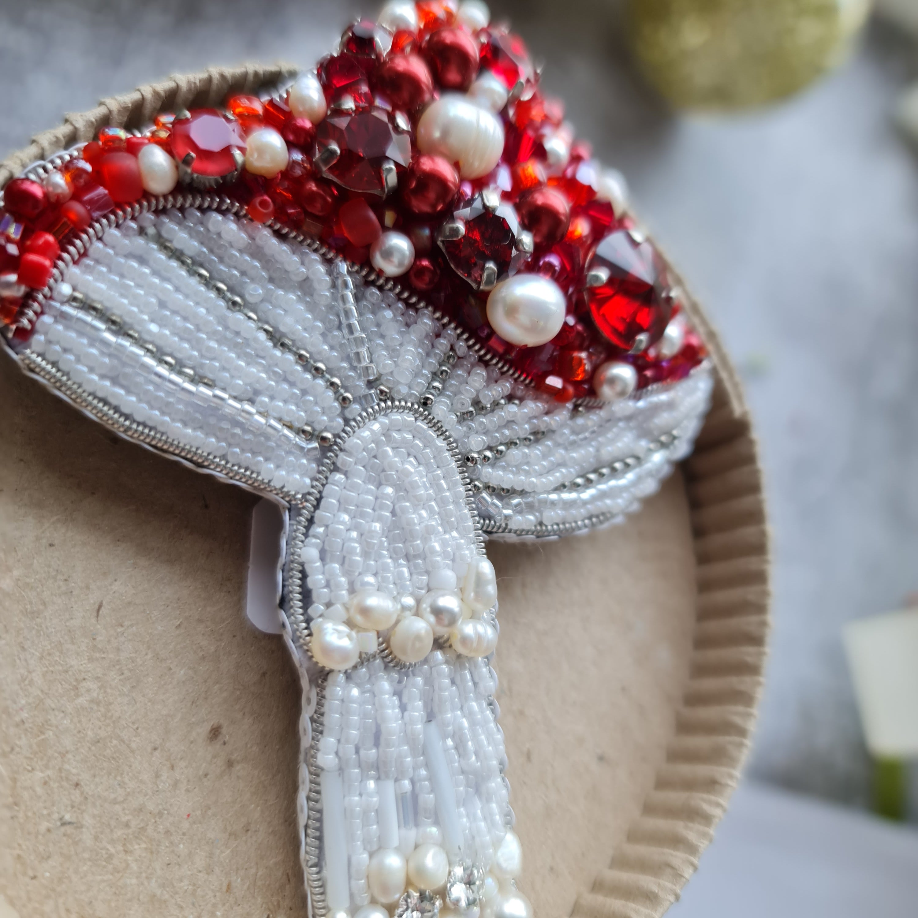 Decorative brooch with red and white stones on a cardboard backing