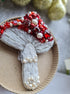 Decorative brooch with red and white stones on a cardboard backing