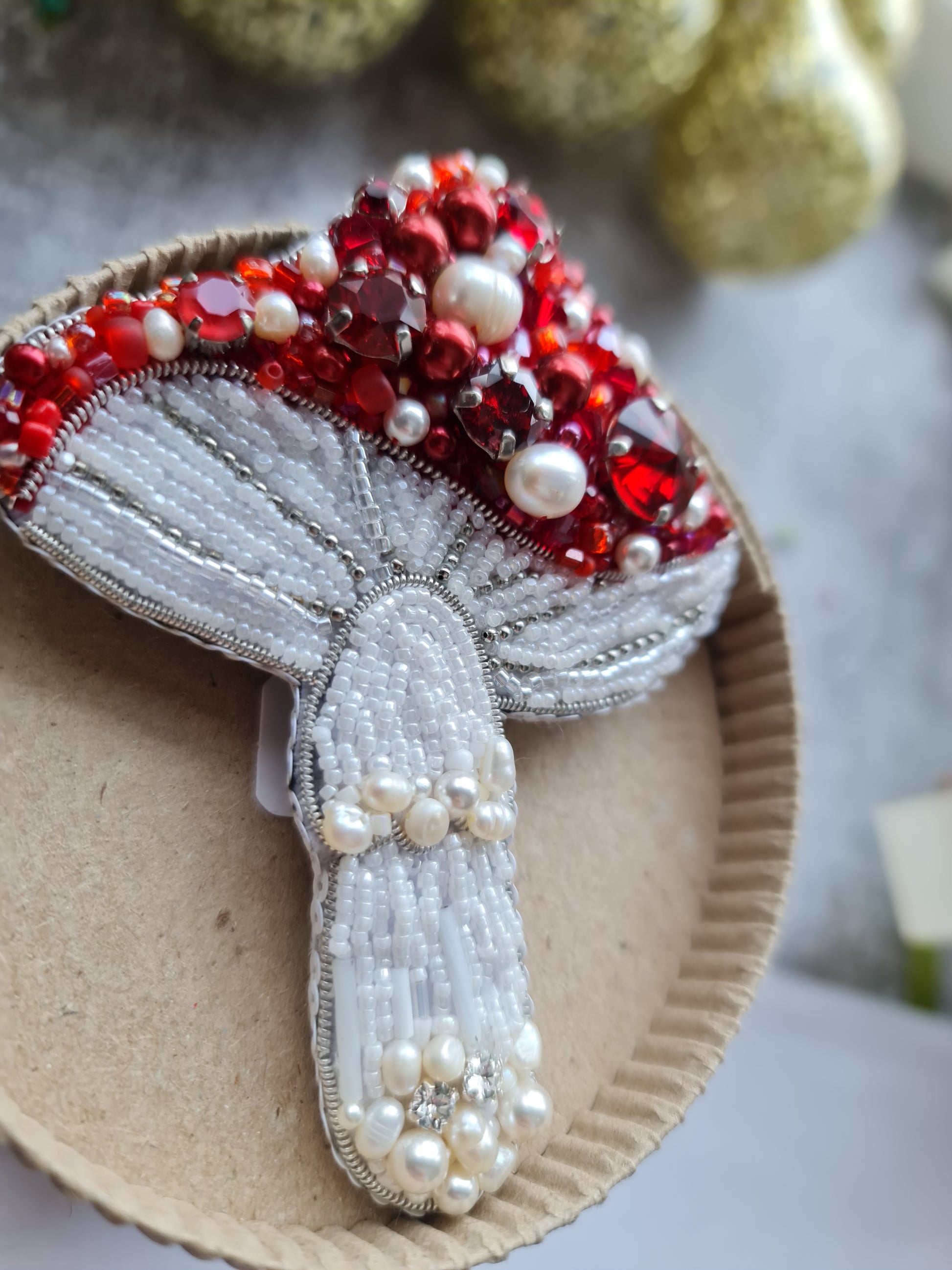 Decorative brooch with red and white stones on a cardboard backing