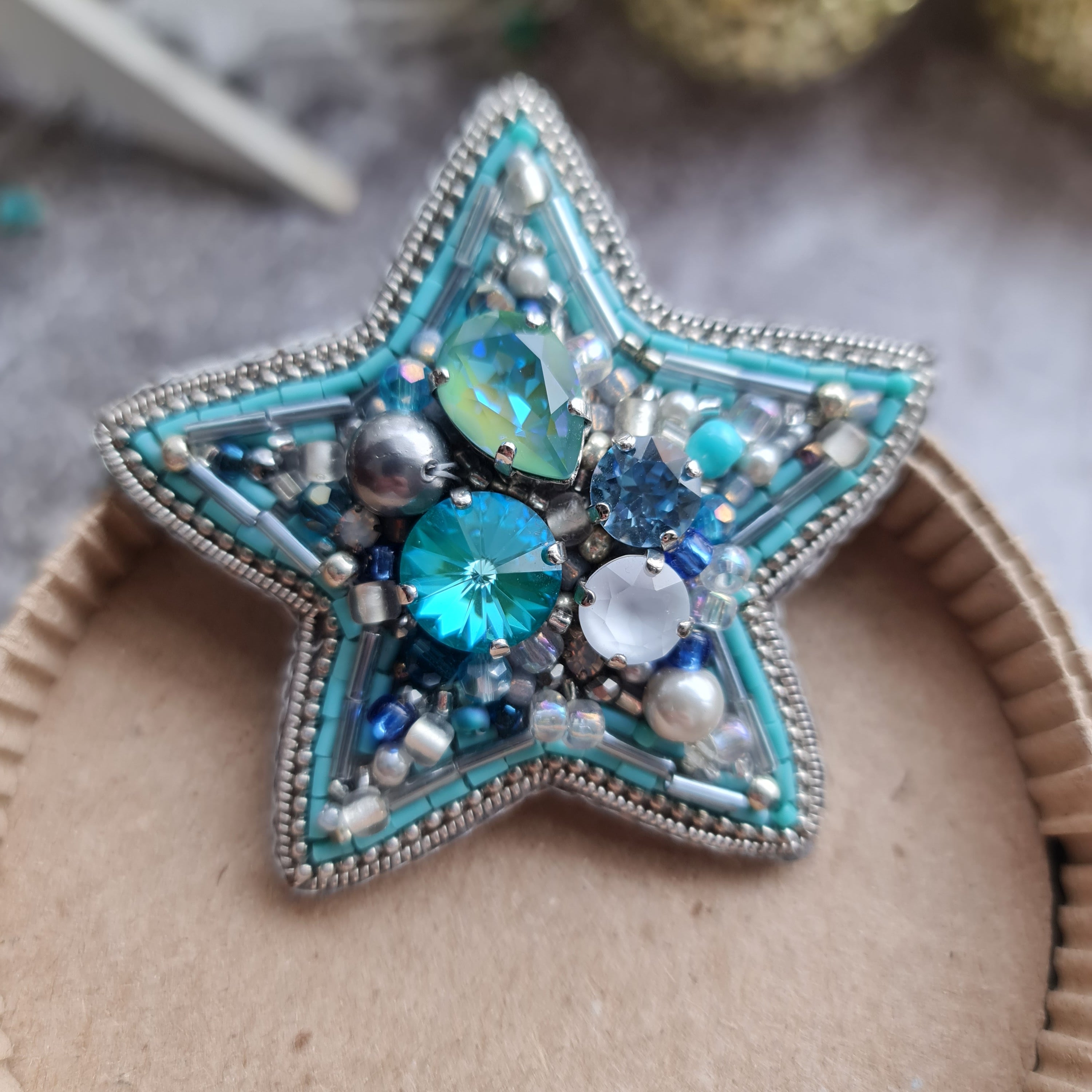Star-shaped decorative item with blue and silver embellishments on a cardboard surface.