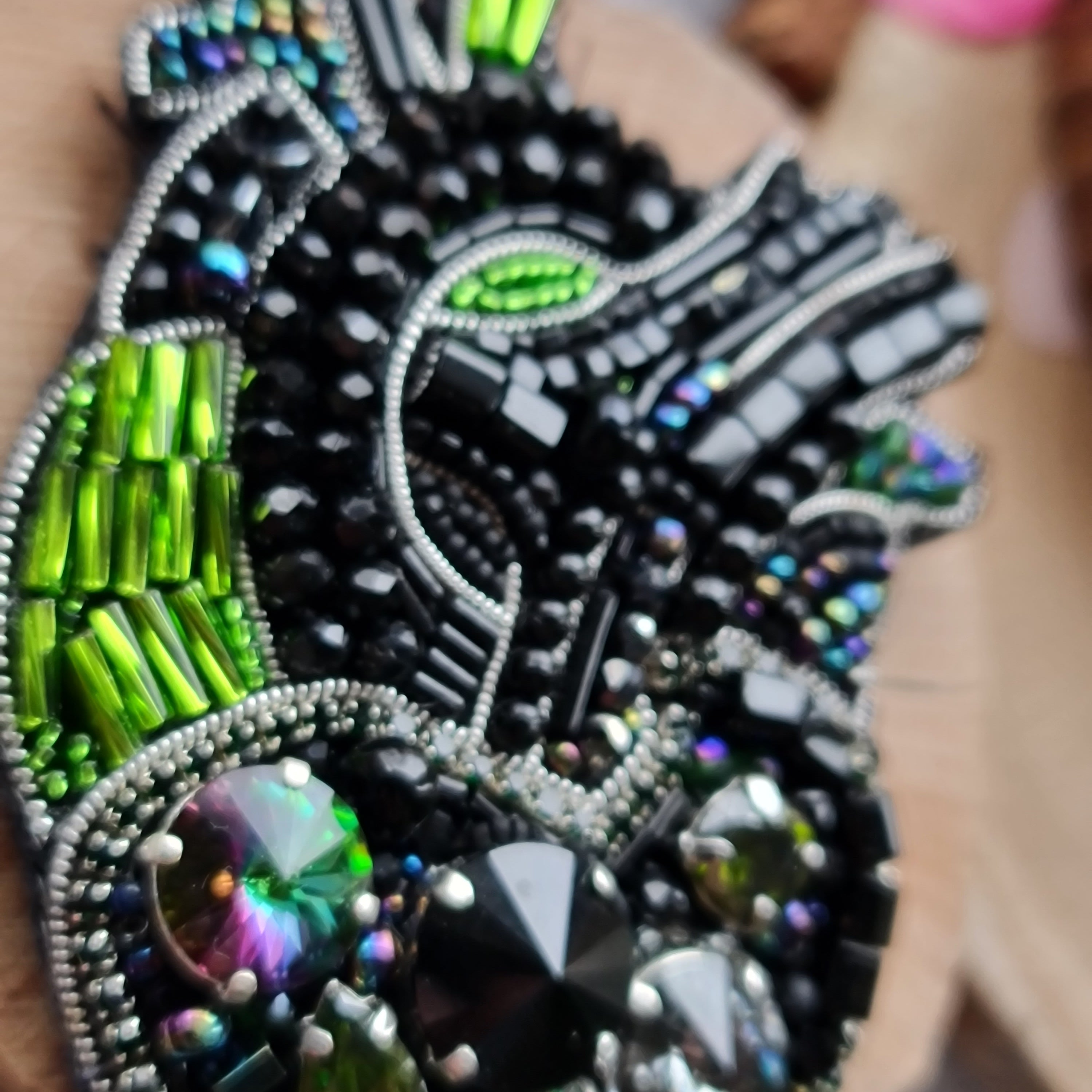 Decorative brooch with intricate beadwork on a hand