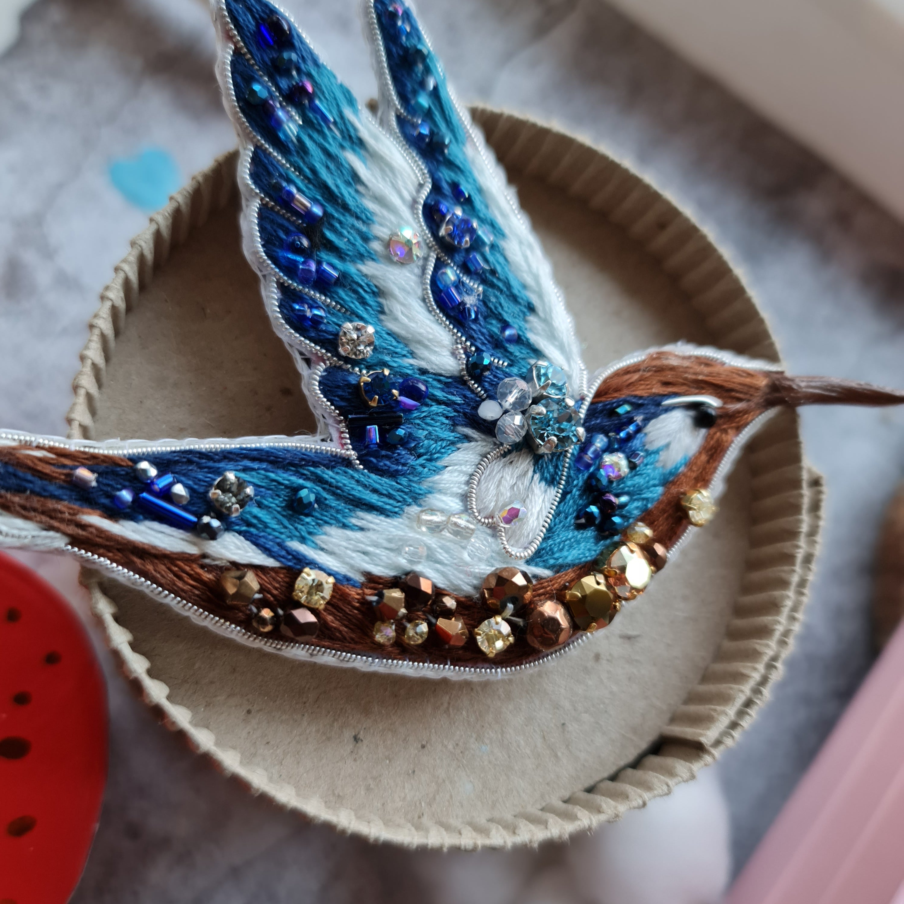Blue hummingbird beaded brooch hand embroidered with blue white and brown thread, crystals, beads, and sparkling bird details