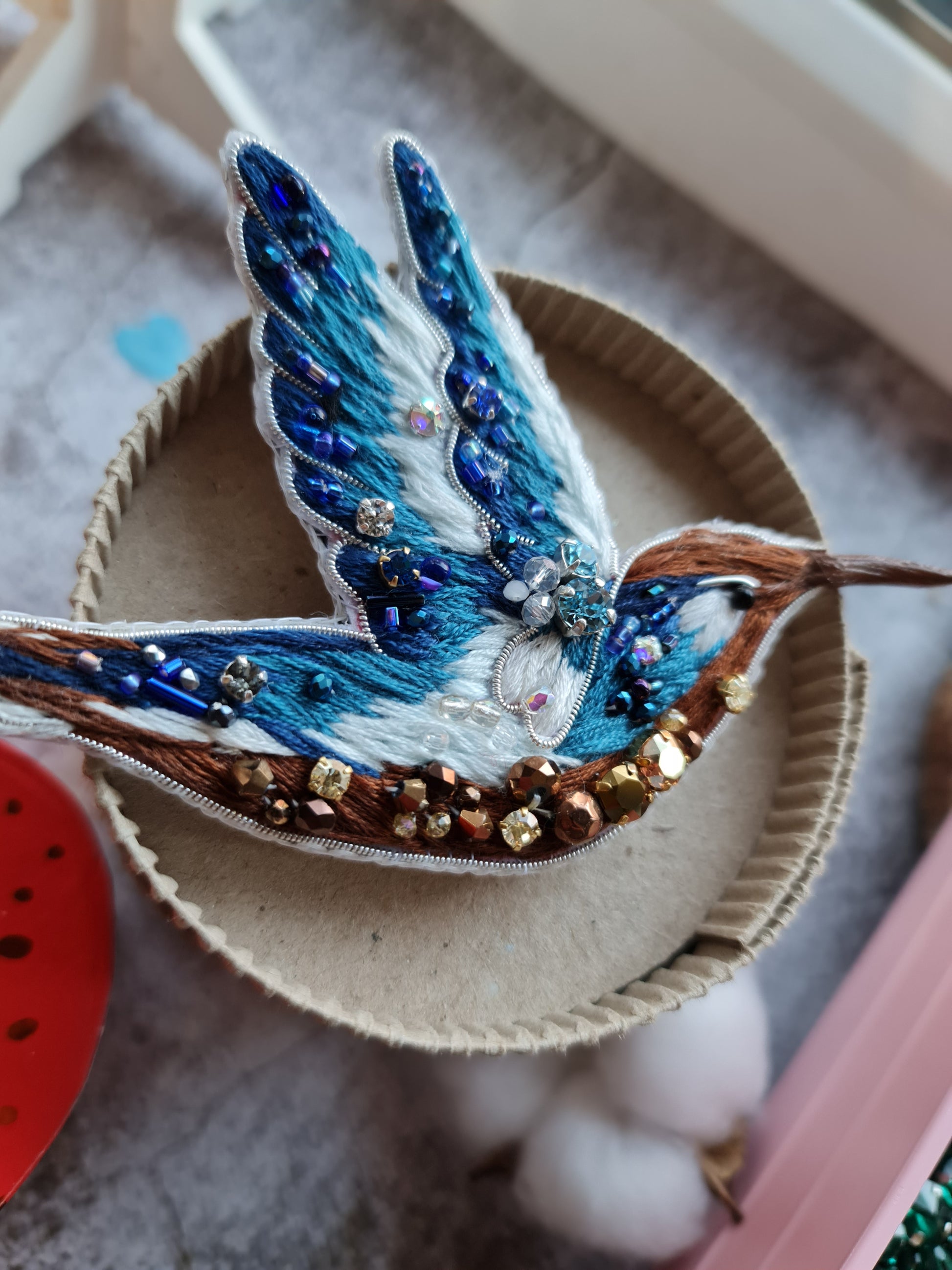 Blue hummingbird beaded brooch hand embroidered with blue white and brown thread, crystals, beads, and sparkling bird details