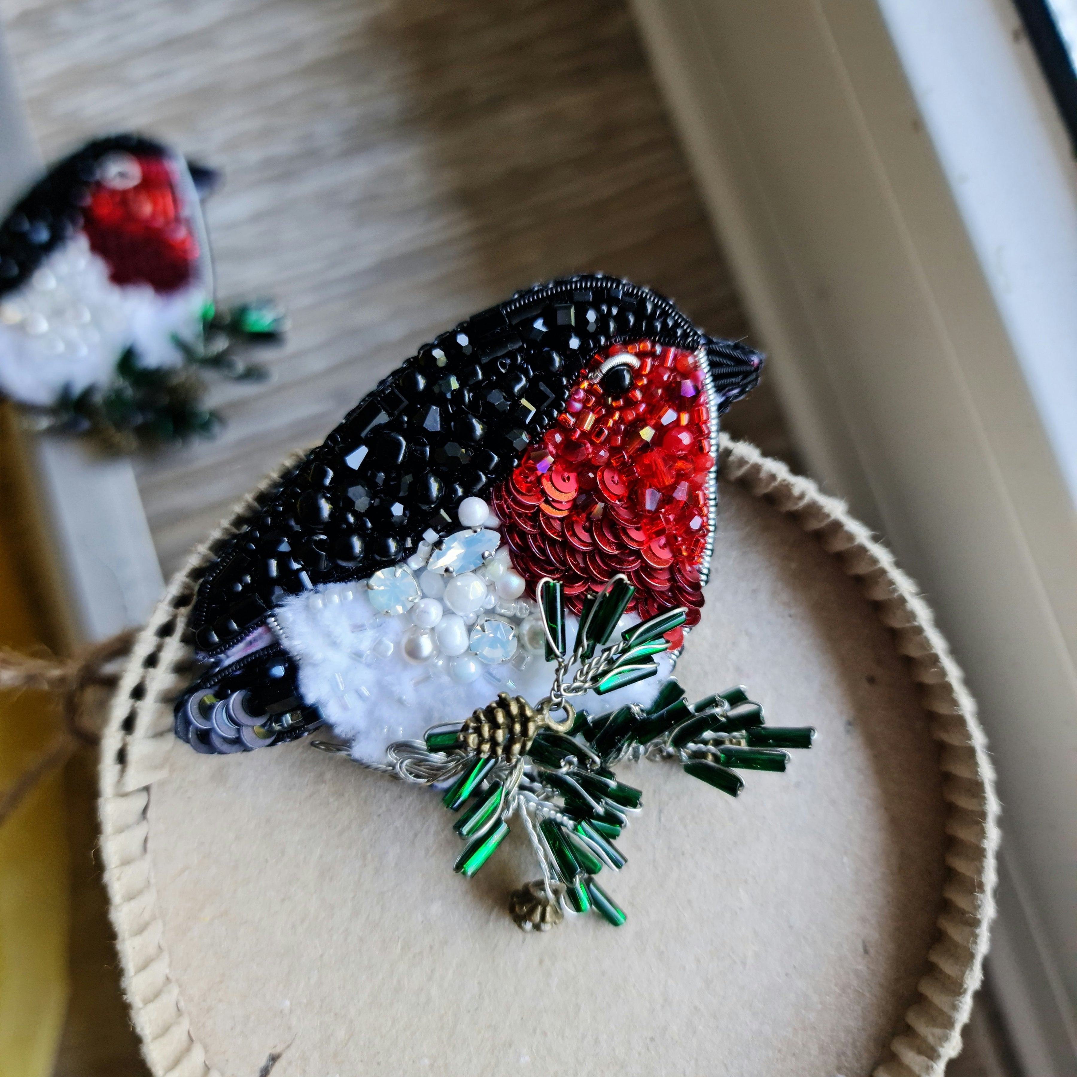 Bullfinch beaded brooch hand embroidered with red, black, white, and green beads, crystals, sequins, and winter bird details