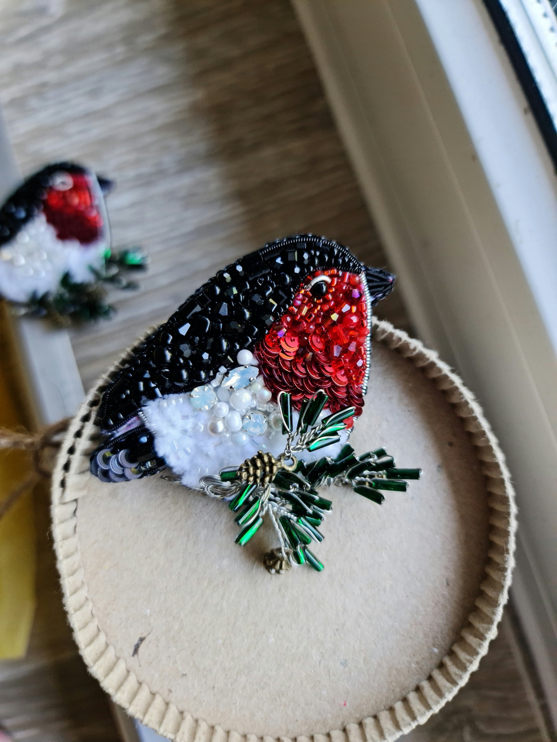 Bullfinch beaded brooch hand embroidered with red, black, white, and green beads, crystals, sequins, and winter bird details