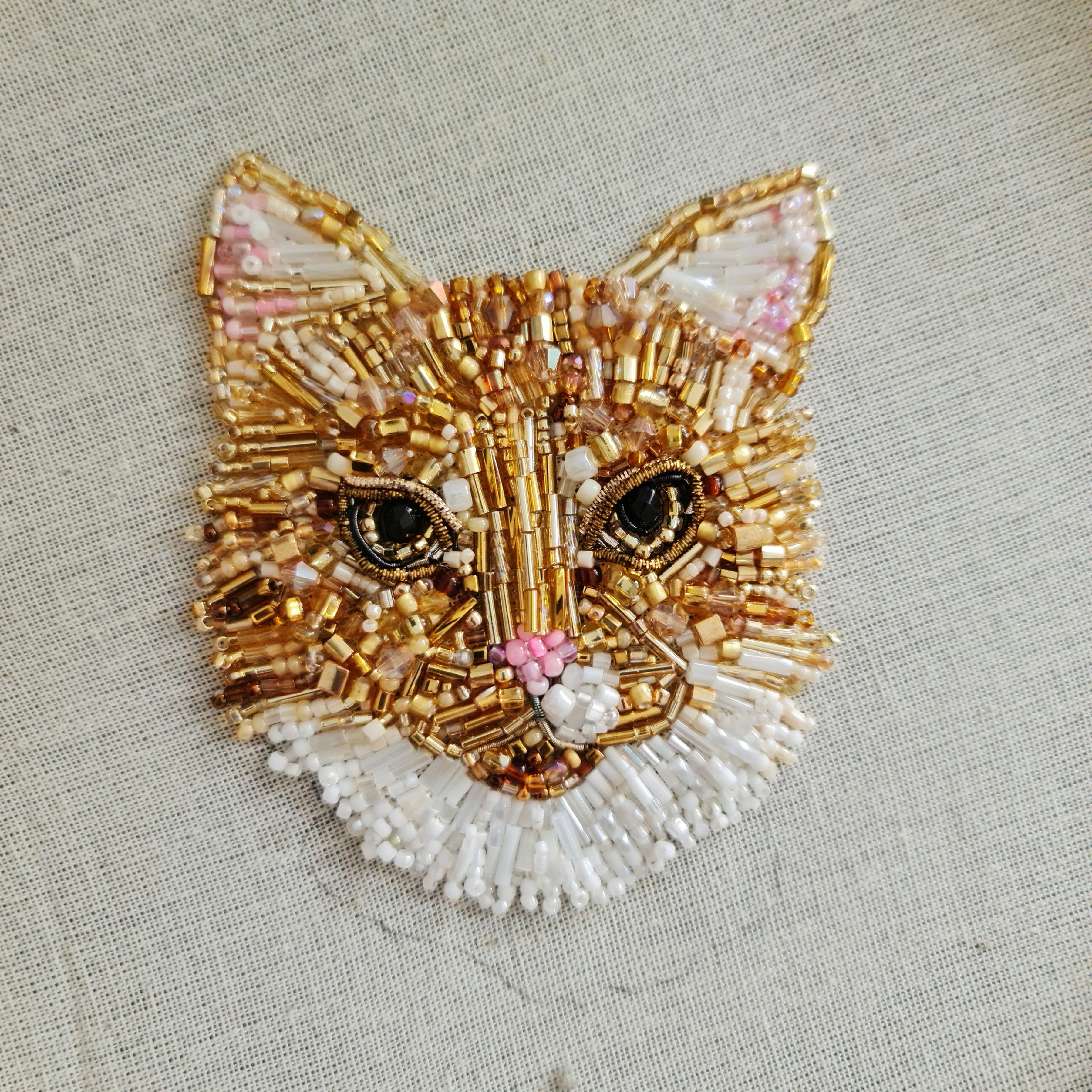 Embroidered cat face design on fabric with a hoop