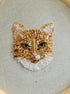 Embroidered cat face design on fabric with a hoop