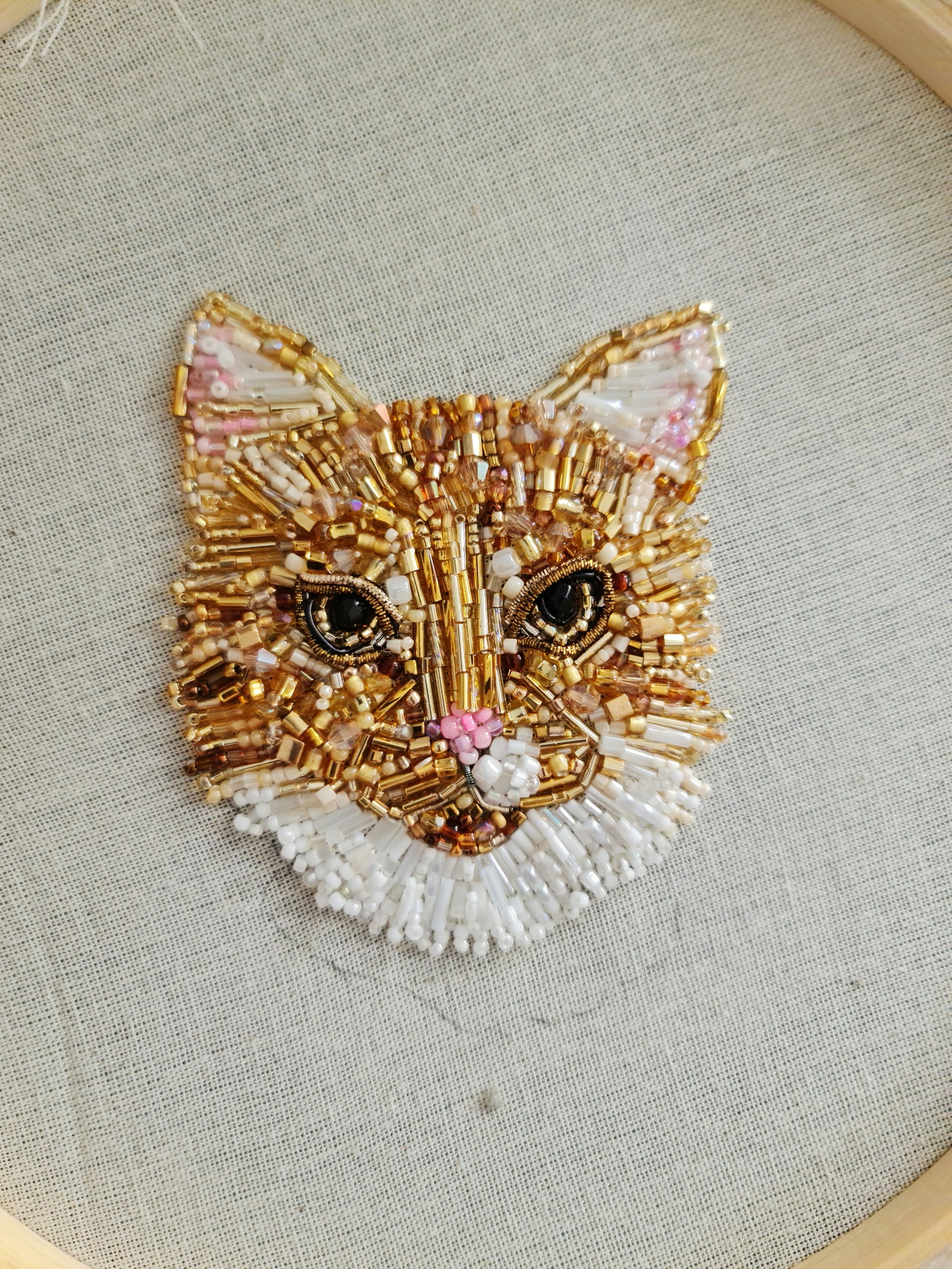 Embroidered cat face design on fabric with a hoop