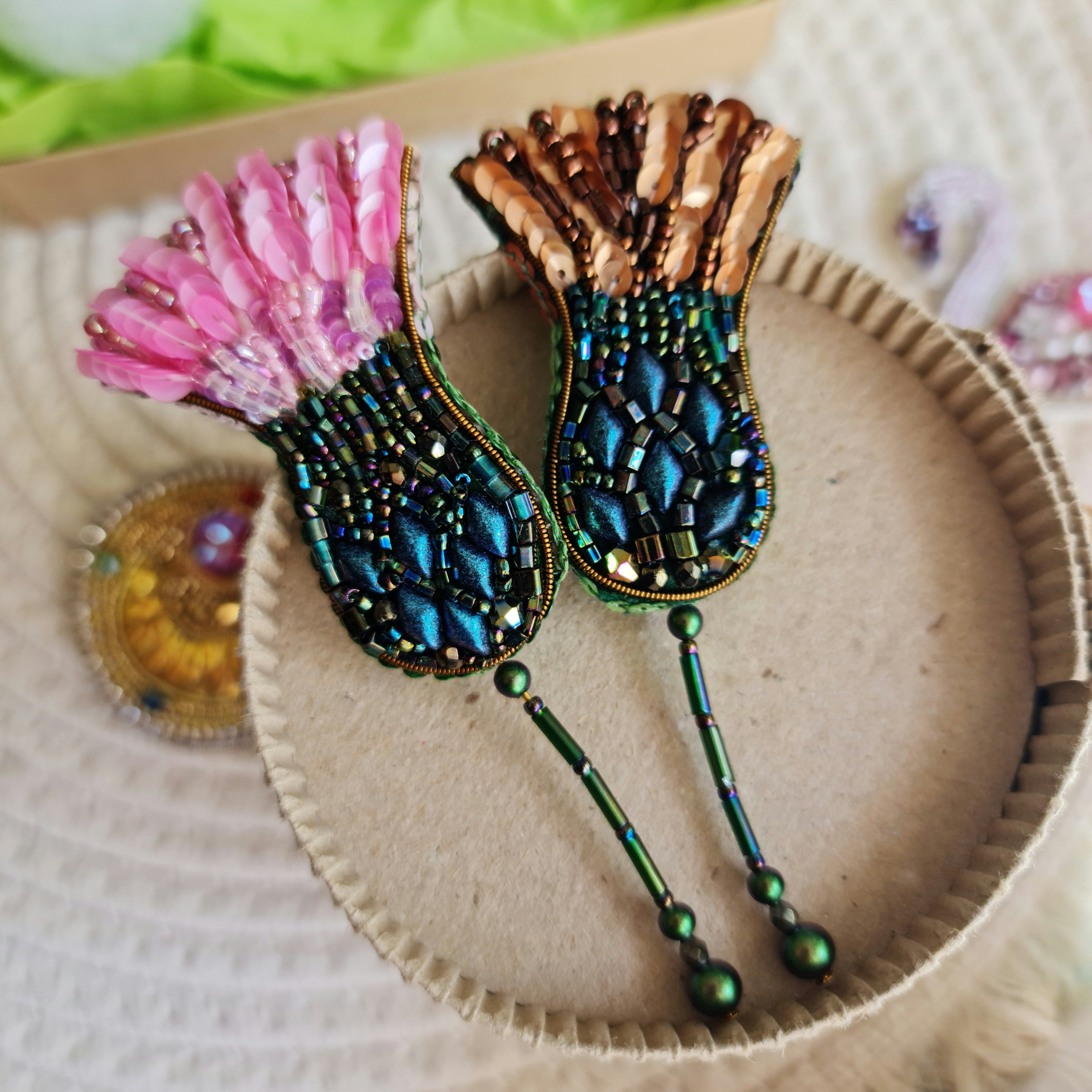 Decorative hair pins with pink tassels and intricate designs on a textured surface.