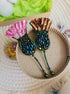 Decorative hair pins with pink tassels and intricate designs on a textured surface.