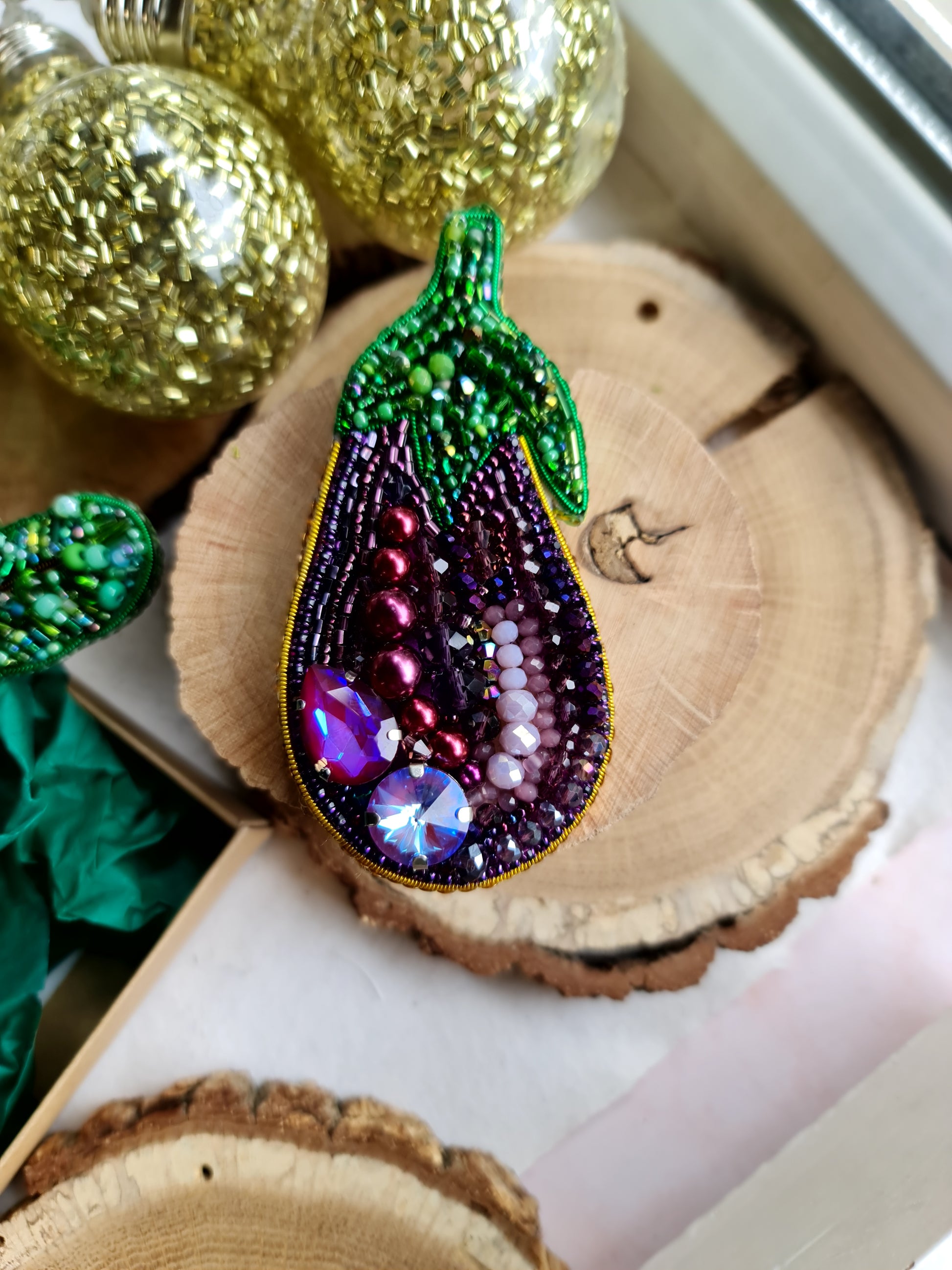 Decorative eggplant-shaped ornament with gemstones on a wooden surface