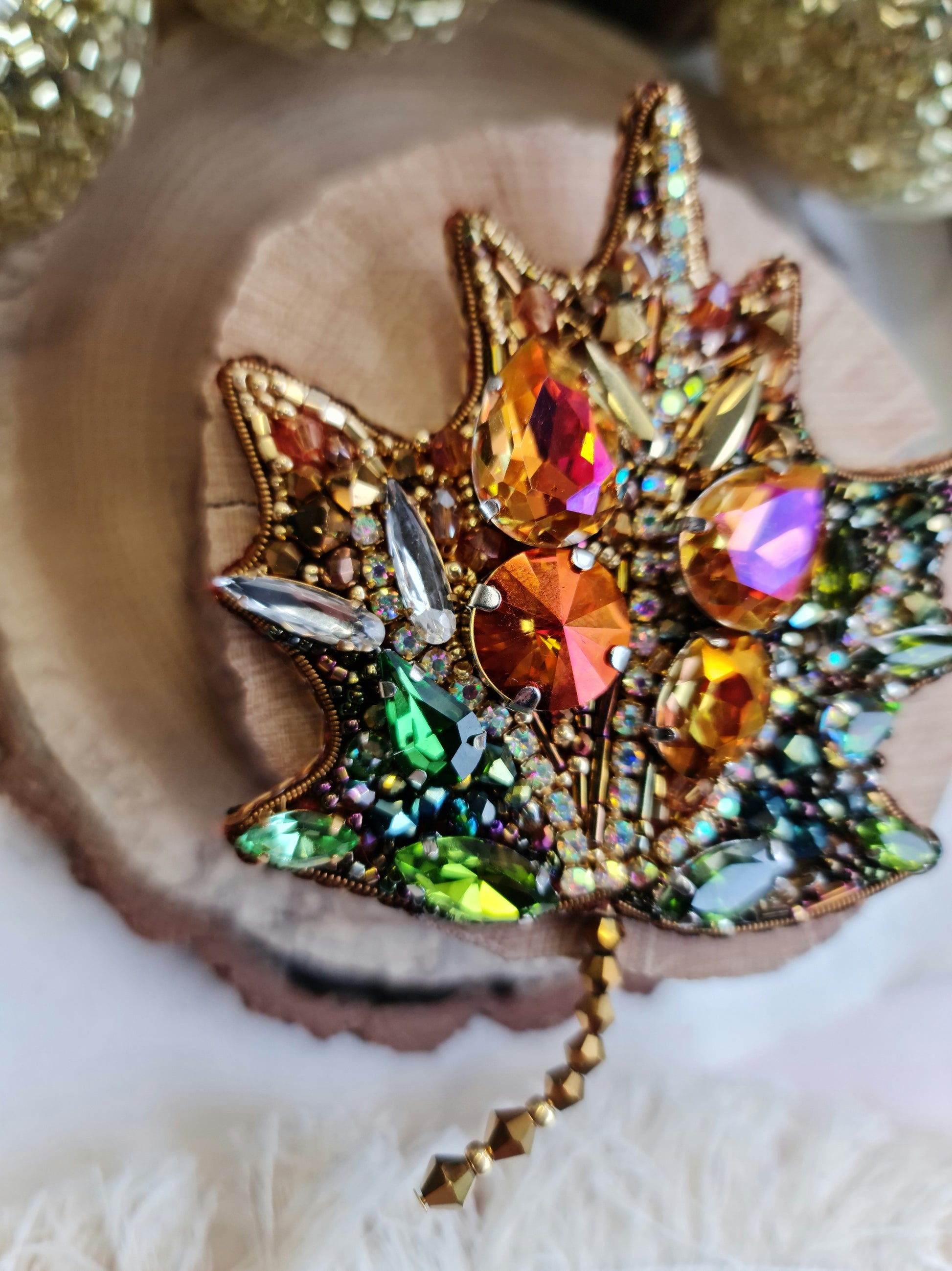 Decorative brooch with colorful gemstones on a wooden surface