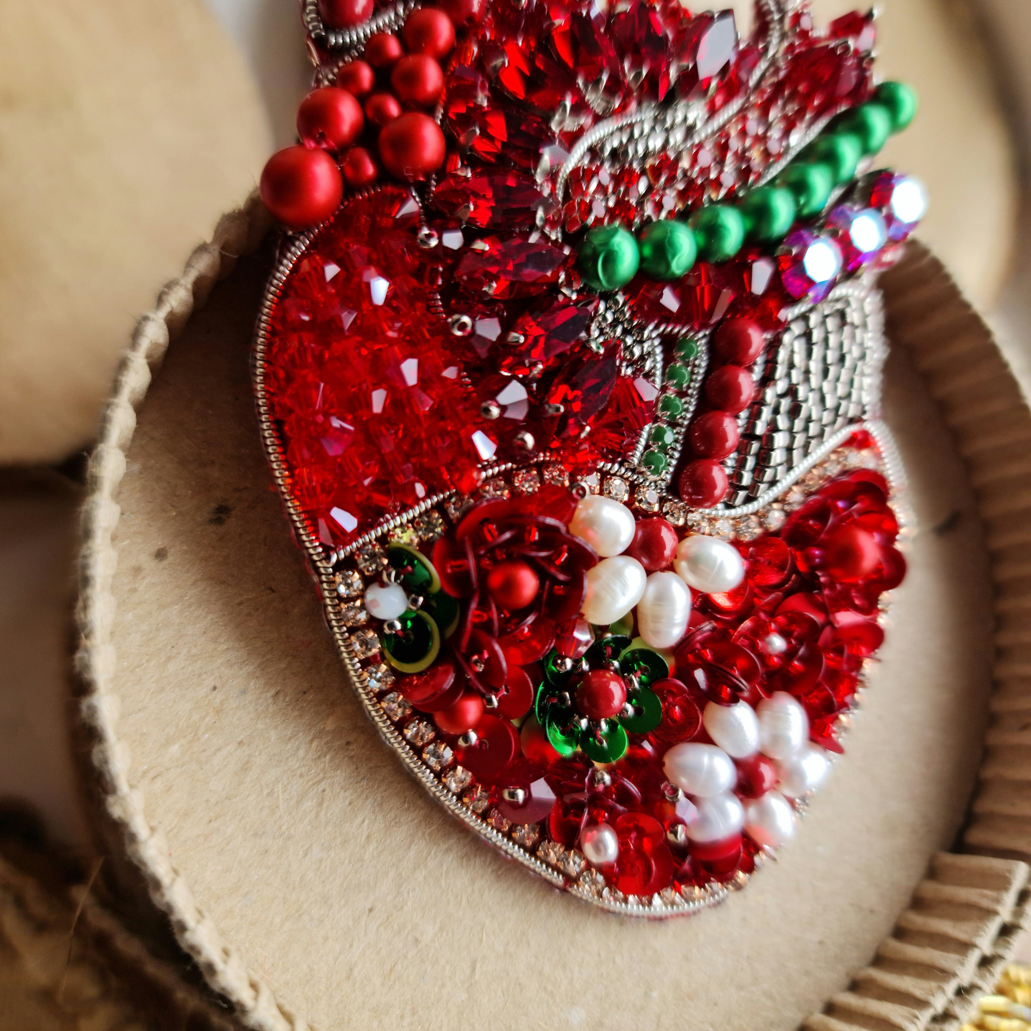 Decorative heart with red, green, and white embellishments on a textured surface