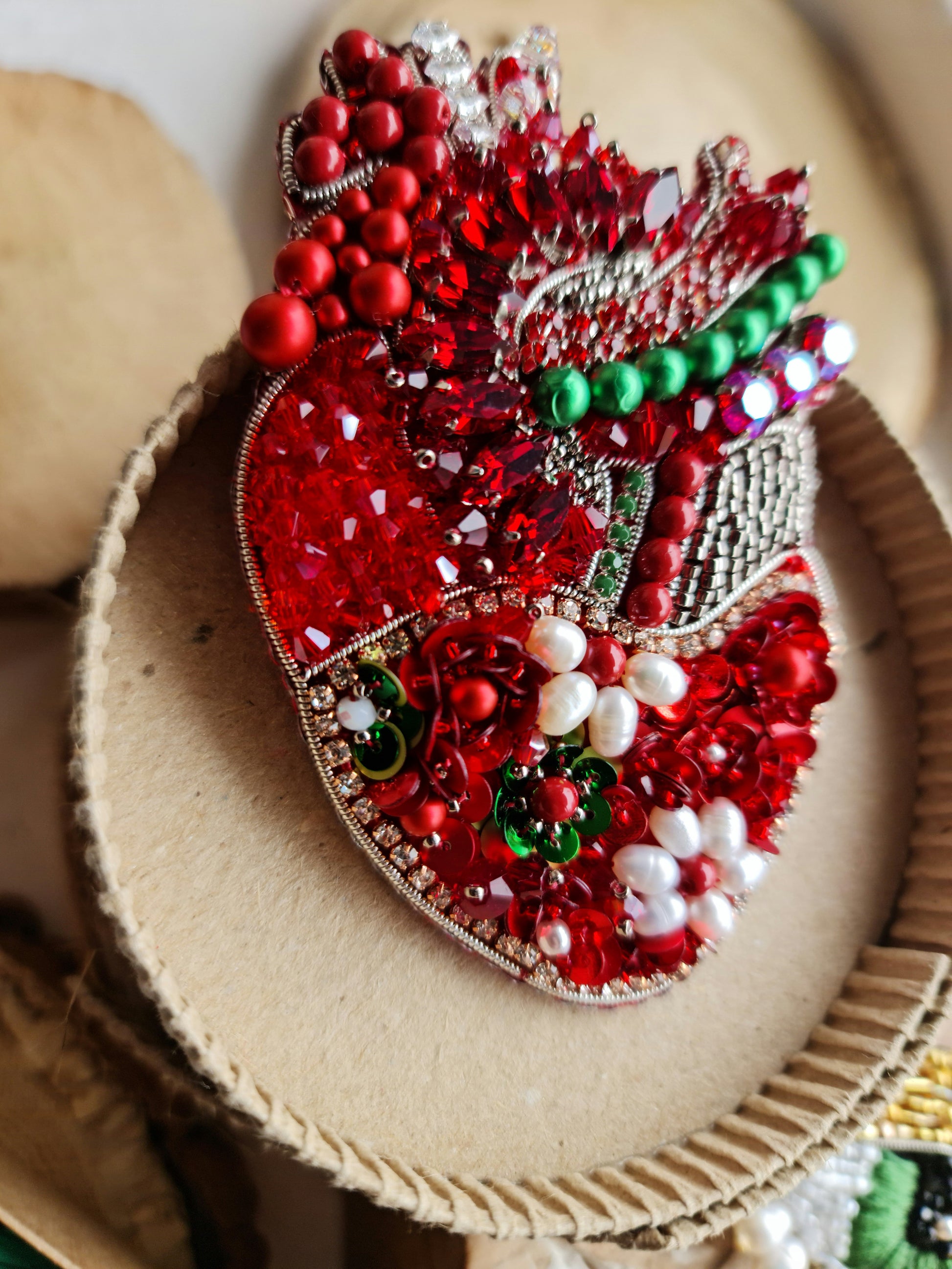 Decorative heart with red, green, and white embellishments on a textured surface