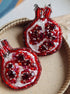 Red beaded pomegranate earrings on a textured surface