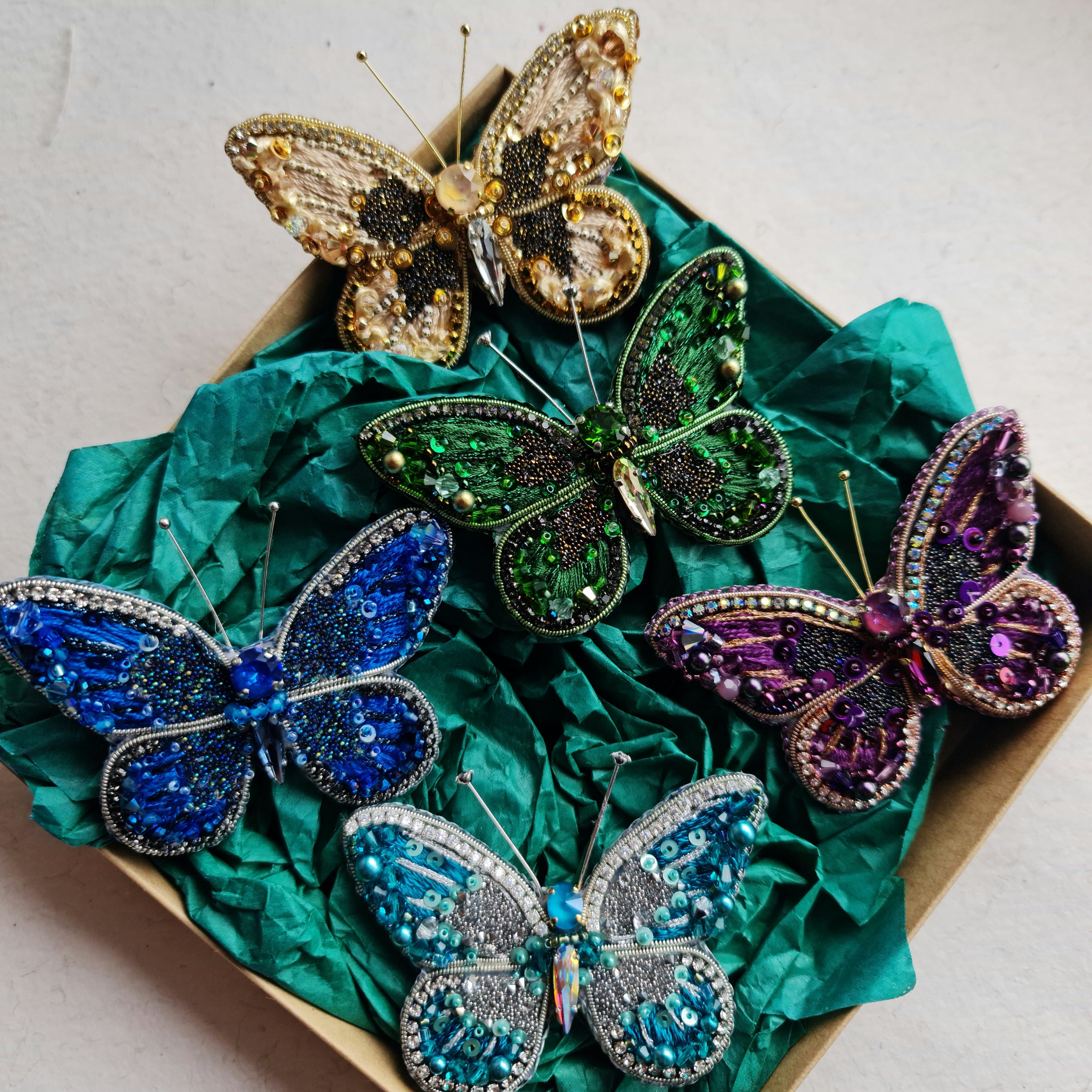 Colorful butterfly-shaped brooches on a green fabric background