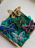 Colorful butterfly-shaped brooches on a green fabric background