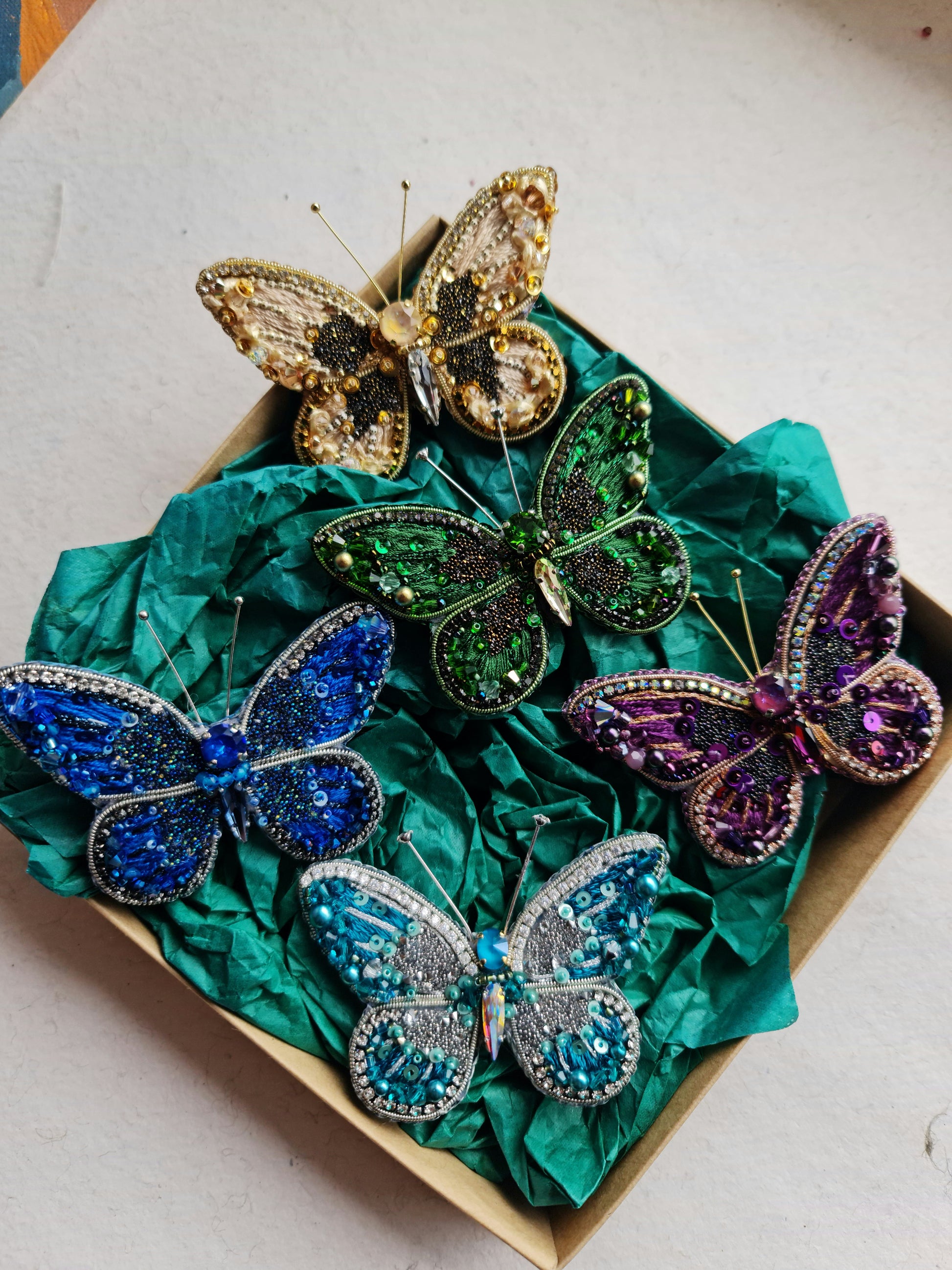 Colorful butterfly-shaped brooches on a green fabric background