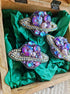 Decorative brooches with gemstones on green fabric inside a wooden box