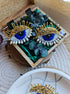 Close-up view of the intricate beadwork on the blue eye brooch, showcasing shimmering glass beads, crystals, and plastic beads fixed onto felt