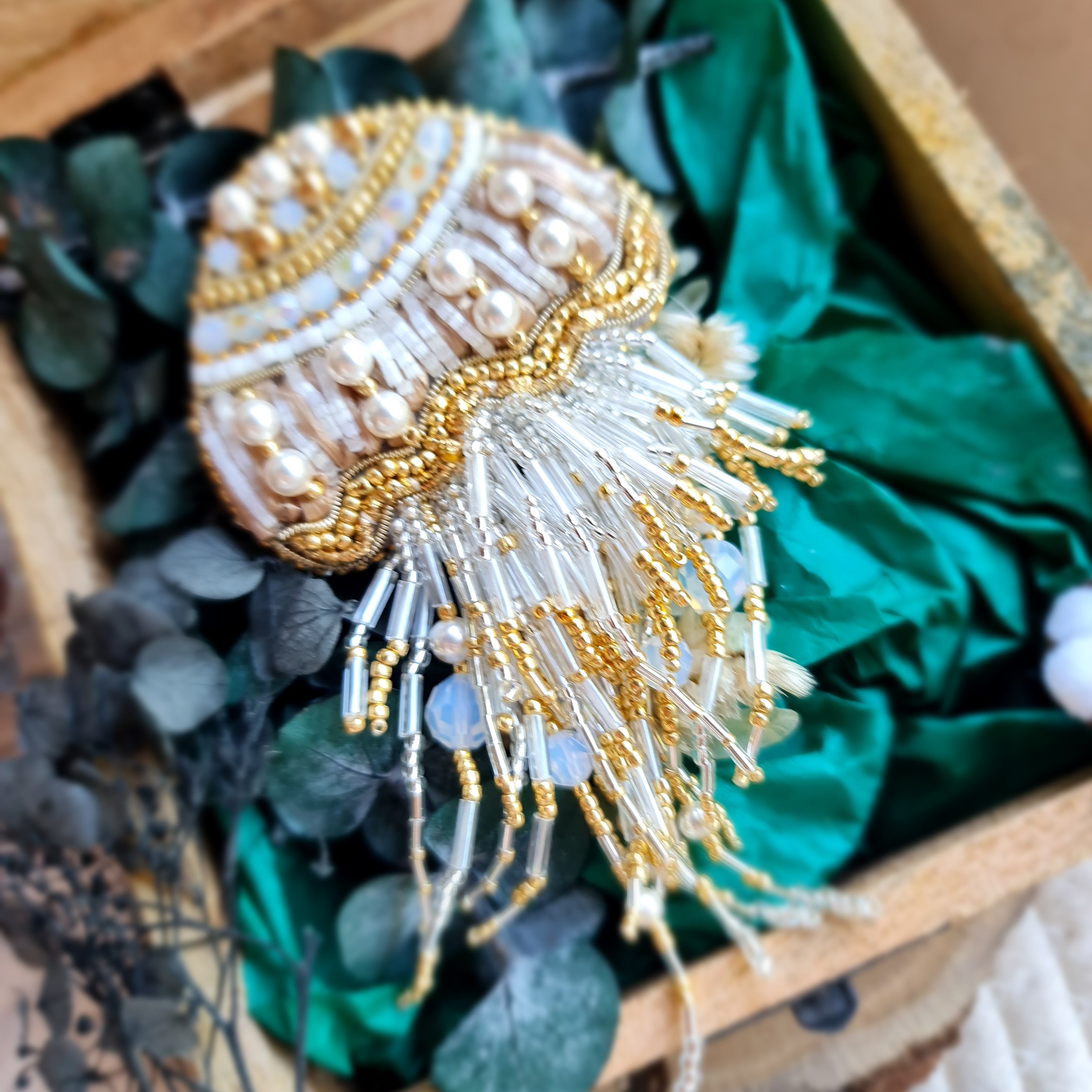 Decorative brooch with gold and white details on a green fabric background