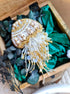 Decorative brooch with gold and white details on a green fabric background