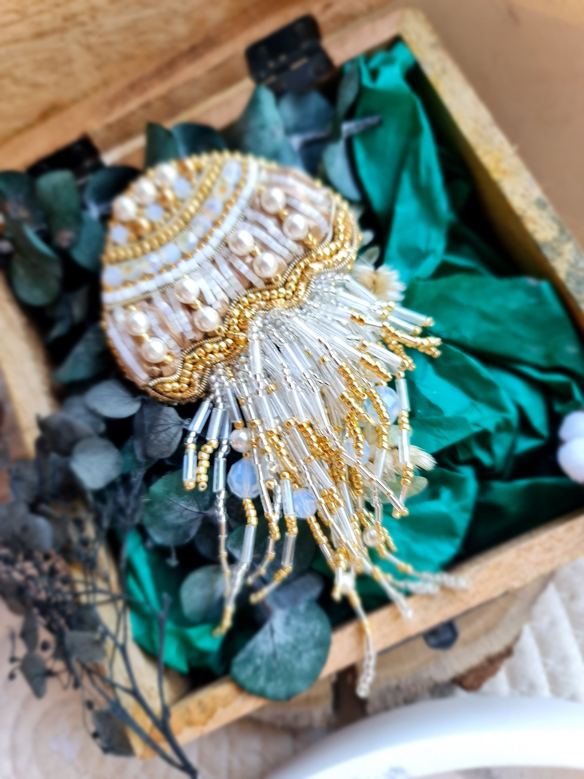 Decorative brooch with gold and white details on a green fabric background
