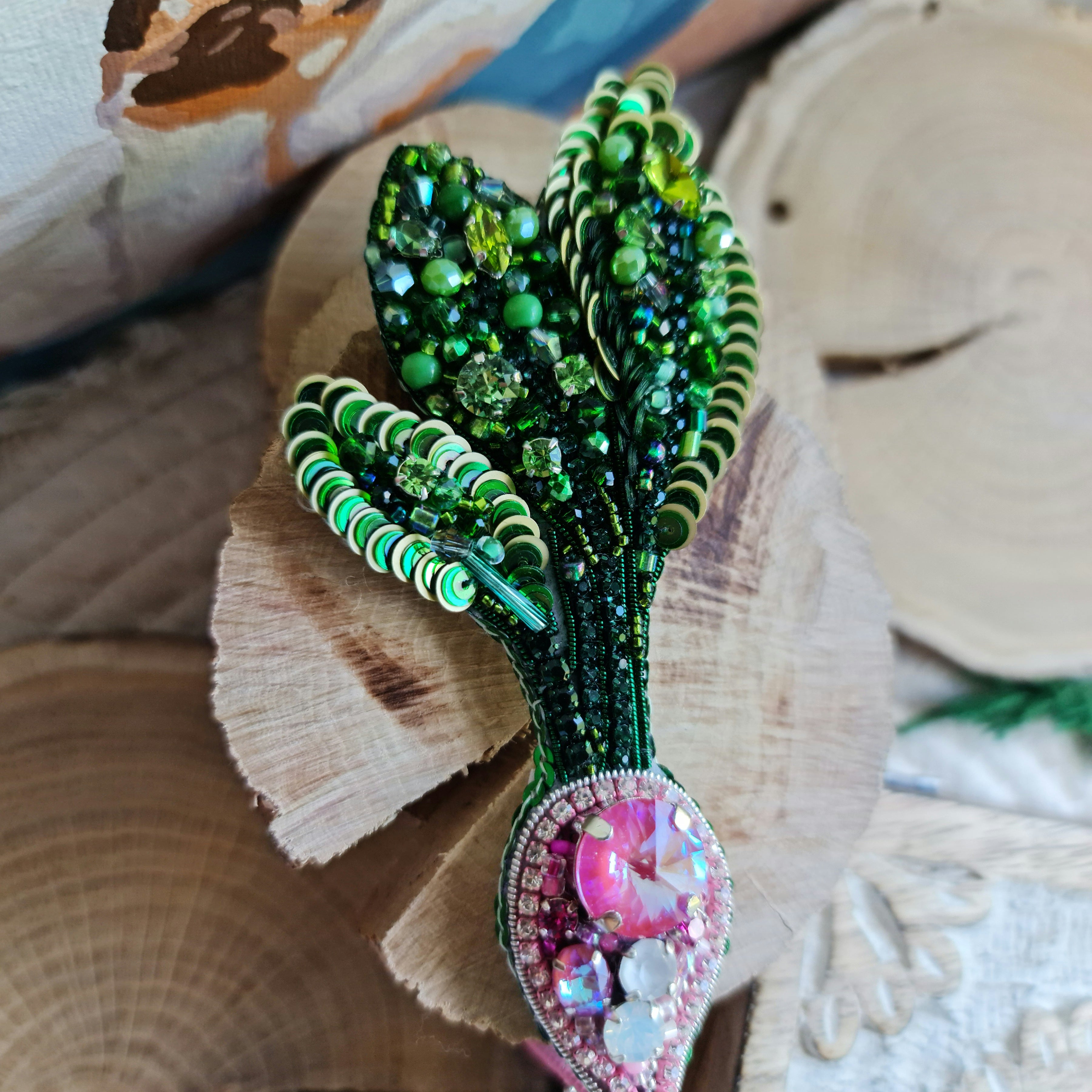 Handmade radish beaded brooch with green leaves, a pink crystal center, and sparkling embroidered details