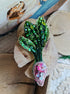 Handmade radish beaded brooch with green leaves, a pink crystal center, and sparkling embroidered details