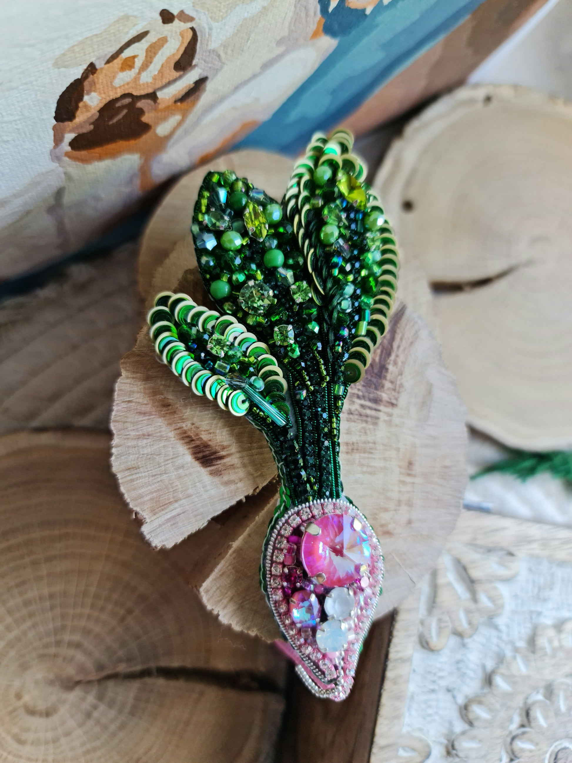 Handmade radish beaded brooch with green leaves, a pink crystal center, and sparkling embroidered details