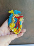 Close-up of the anatomical heart brooch showing detailed stitching and vibrant embroidered patterns.