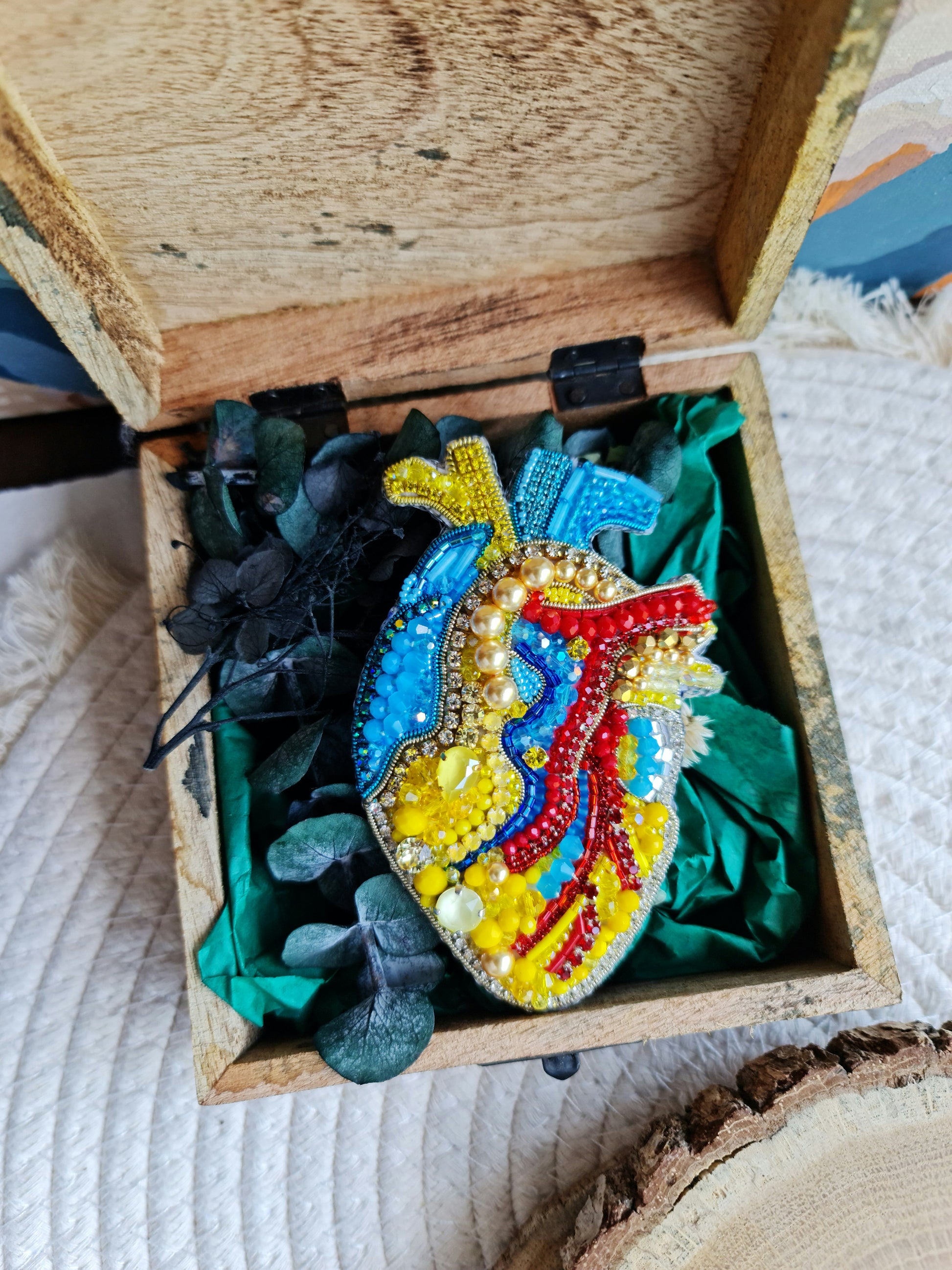 Close-up of the anatomical heart brooch showing detailed stitching and vibrant embroidered patterns.