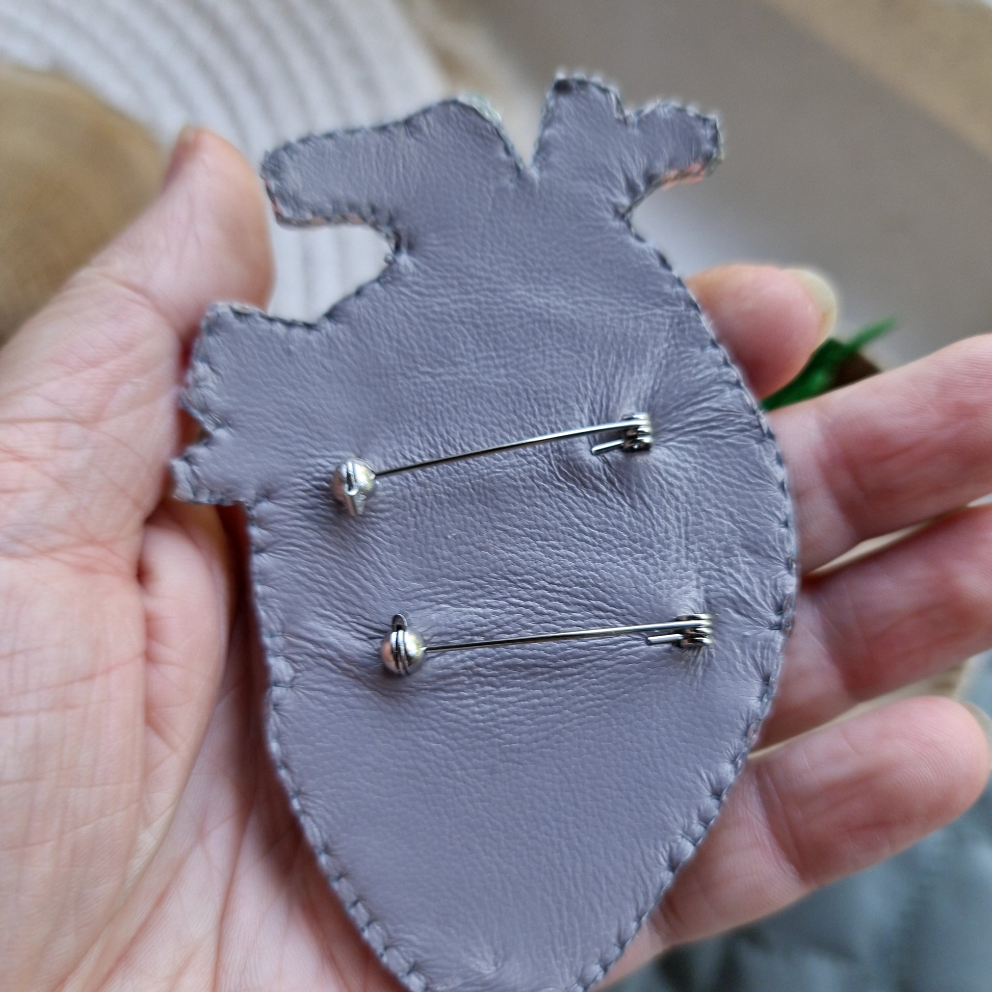 Close-up of the anatomical heart brooch showing detailed stitching and vibrant embroidered patterns.