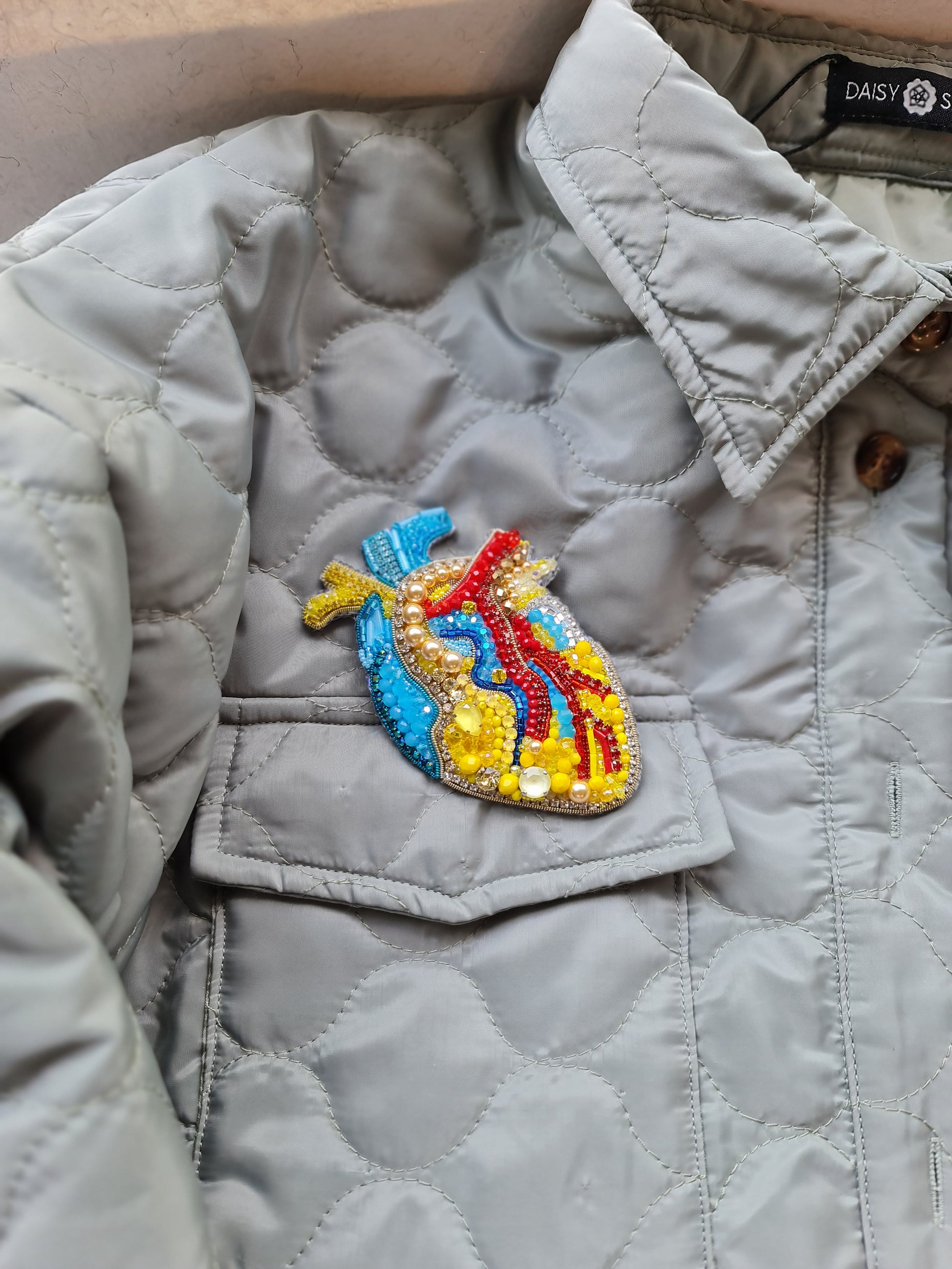 Model wearing the Anatomical Heart Embroidered Brooch pinned on a jacket, highlighting its artistic design and craftsmanship