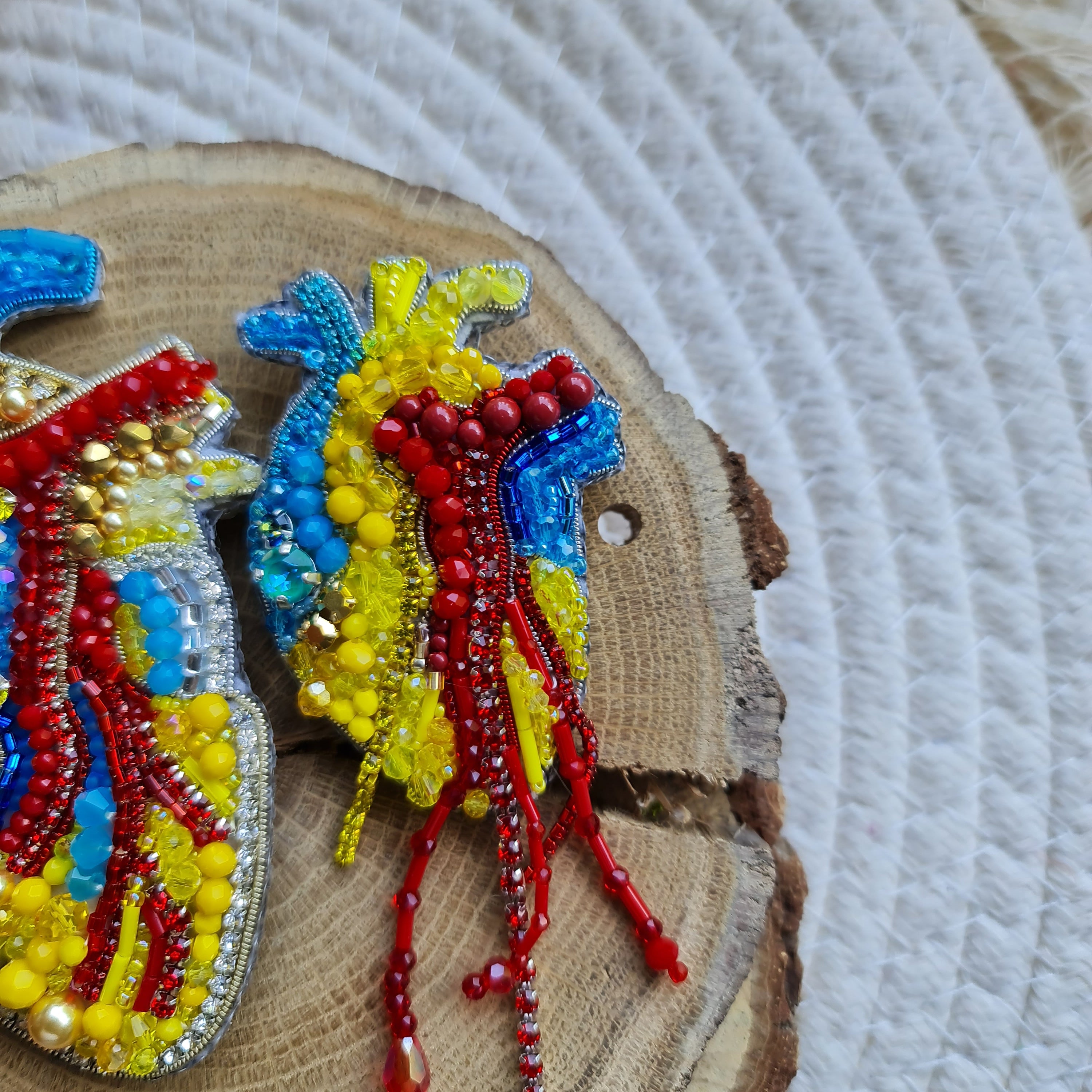 Anatomical heart beaded brooch hand embroidered with blue yellow and red beads, crystals, and sparkling chain details